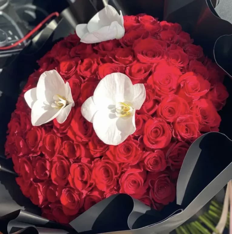 Red Luxe Ramo Buchon - Make a bold and unforgettable statement with our Red Luxe Ramo Buchón, a lavish arrangement crafted for those who love elegance with impact. This stunning bouquet features a perfectly rounded dome of premium red roses, each bloom hand-selected for its rich color, velvety texture, and flawless beauty. Designed in the signature ramo buchón style, it delivers maximum fullness, luxury, and presence.  Wrapped in sleek black luxury paper to enhance its vibrant red tones, the Red Luxe Ramo Buchón radiates sophistication and passion. Perfect for anniversaries, romantic surprises, celebrations, or any moment that calls for a dramatic show of love.  A bouquet that speaks volumes—extravagant, modern, and irresistibly beautiful.