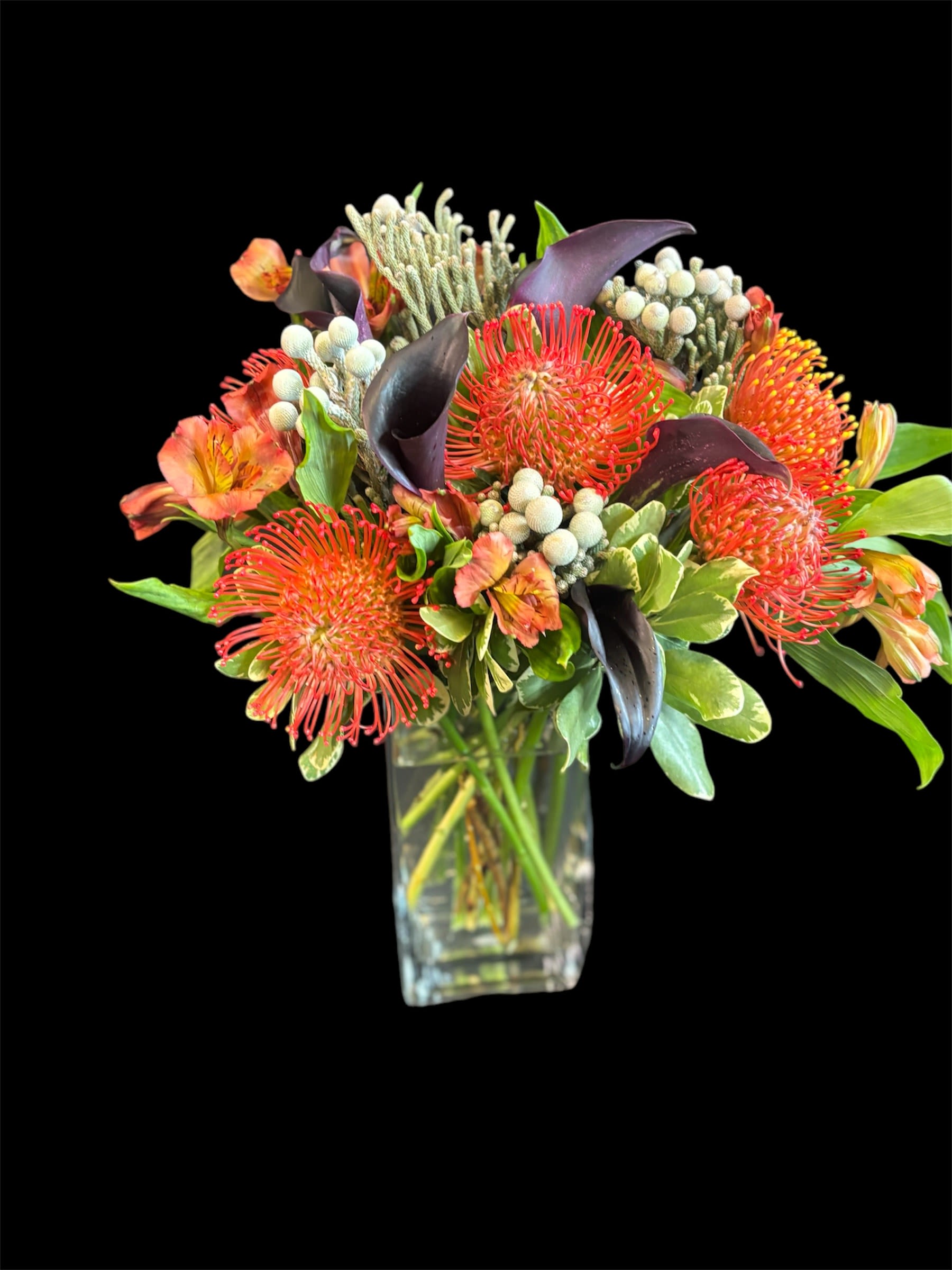 Nocturnal Blaze - Vibrant orange protea, bright orange alstroemeria, and striking black calla lilies arranged beautifully in a rectangular glass vase.