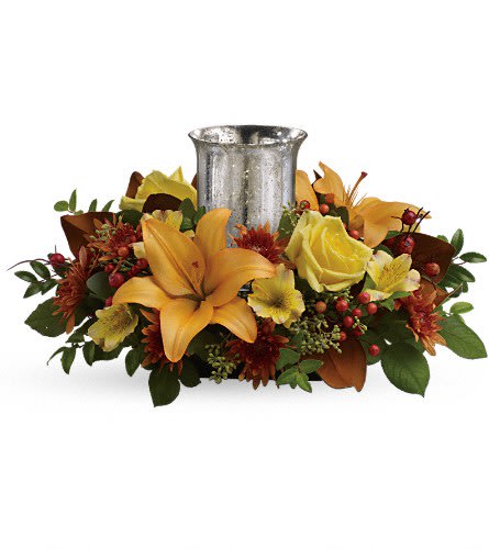 Glowing Gathering Centerpiece by Teleflora - Give a fall gathering a special glow with this wonderfully vibrant autumnal centerpiece featuring roses and lilies around a shimmering mercury glass hurricane. This beautiful arrangement features yellow roses peach asiatic lilies yellow alstroemeria bronze cushion chrysanthemums seeded eucalyptus huckleberry and orange berries. Delivered in an exclusive silver Mercury Glass hurricane.Approximately 18&quot; W x 10&quot; H Orientation: All-Around As Shown : TFL06-3ADeluxe : TFL06-3BPremium : TFL06-3C