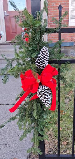 Holiday Swag - Bring a touch of seasonal charm to your home with this elegant winter swag, handcrafted from fresh, fragrant evergreens. Accented with natural pinecones and finished with a stylish bow, it offers a classic yet cozy look perfect for doors, mantels, or stair railings. With its graceful drape and warm winter textures, this swag adds the perfect hint of holiday spirit to any space.