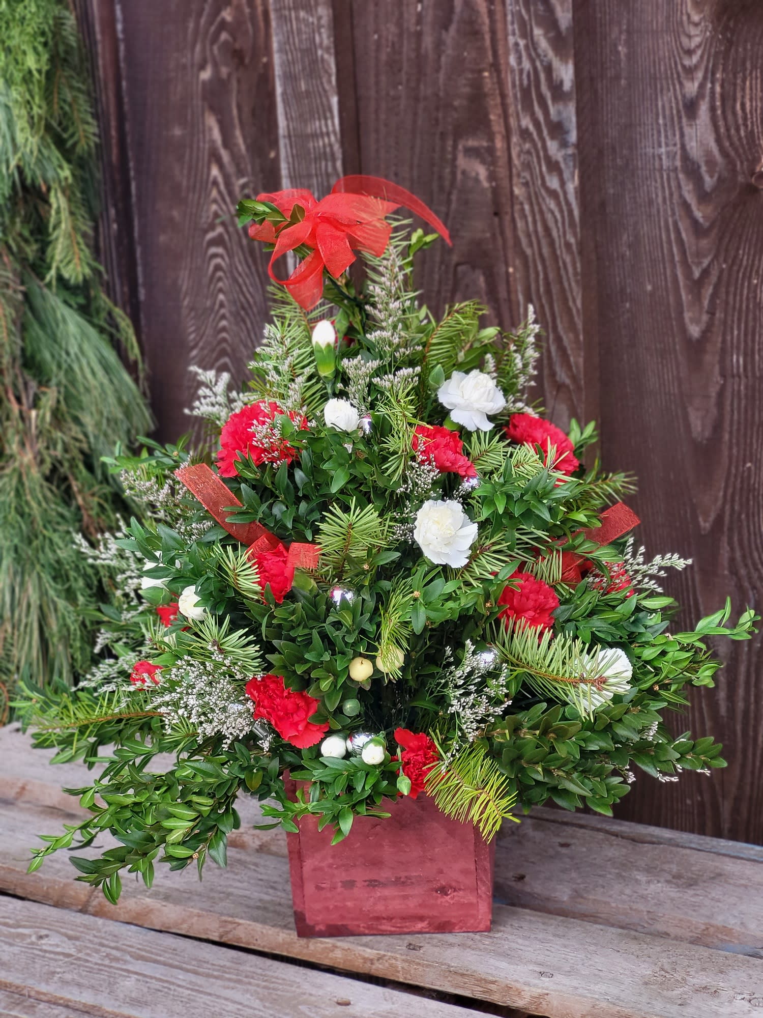 Gather Round - A charming arrangement of a boxwood Christmas tree, in lovely red and white. This long lasting bouquet will help make the holidays even more festive!