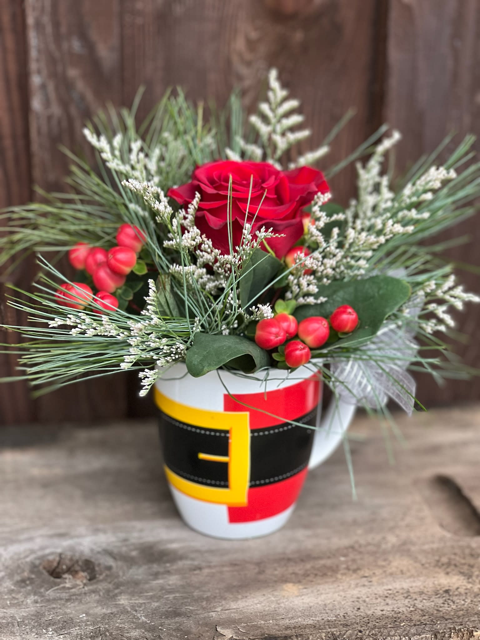 Holly Jolly - A Jolly ole' mug filled with evergreens, a rose and accented with festive blooms!