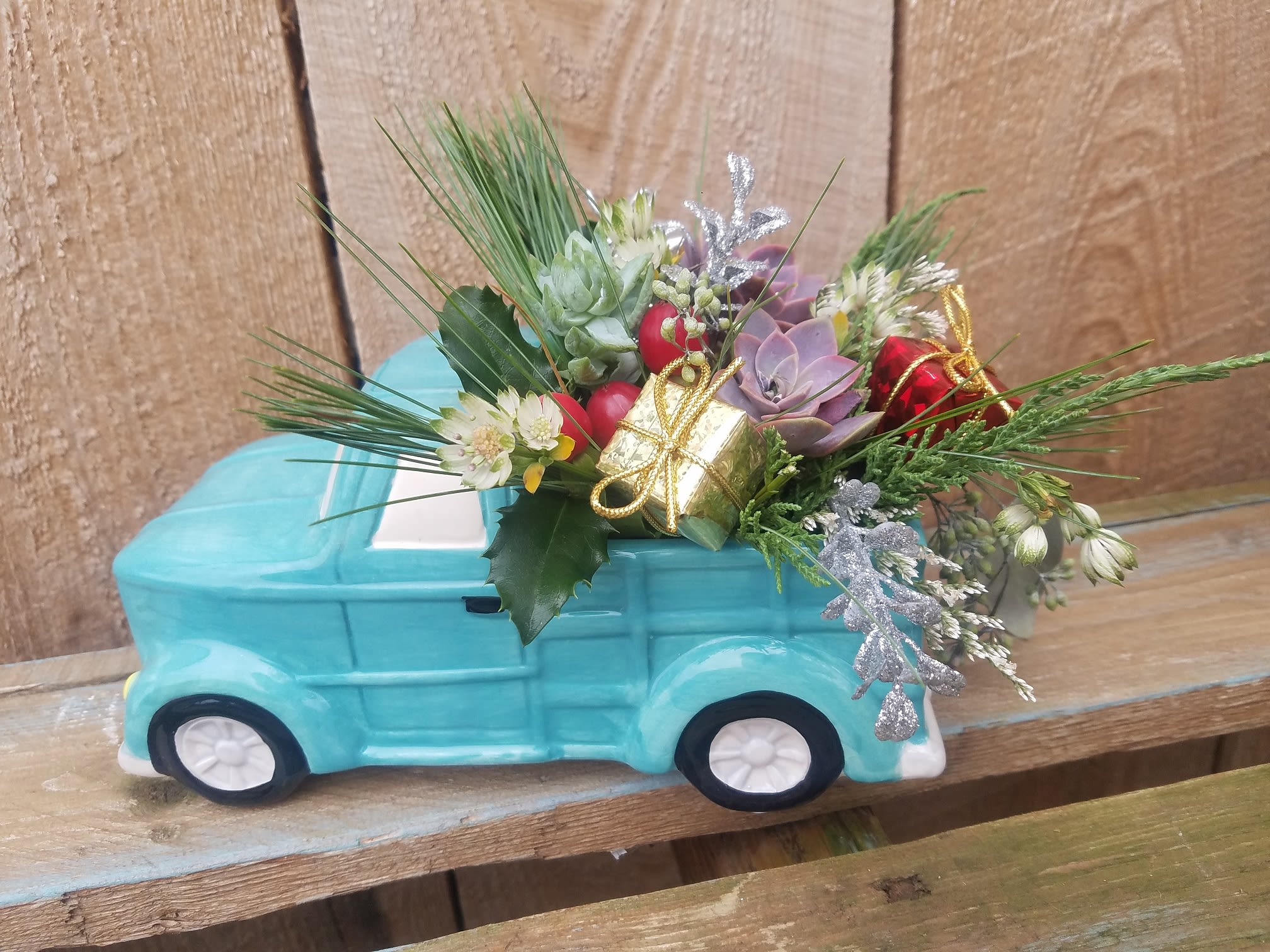 SALE: $45 Down Home Christmas - This charming old fashioned truck has a bed filled with fresh pine, holly, gifts and features an assortment of succulents! This arrangement will look fresh and last well through the holidays and into the new year!