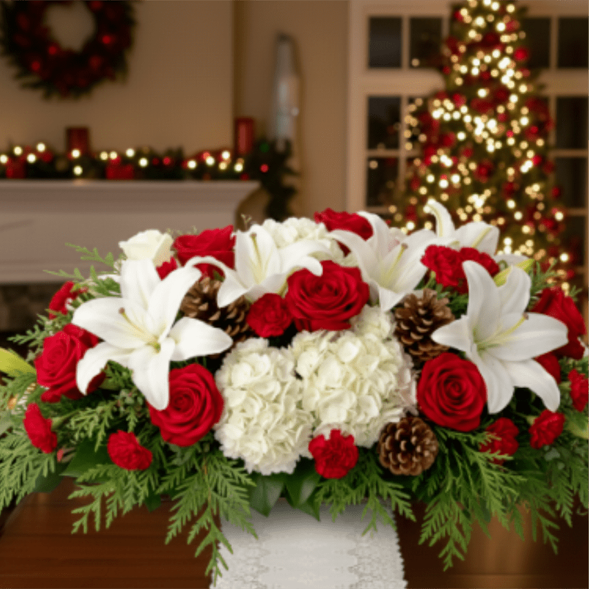 The Classic Christmas Gathering Centerpiece - Make your holiday table shine with our Classic Christmas Gathering Centerpiece. This lavish, low-profile design is perfect for dining tables, allowing guests to converse easily while enjoying the festive display. It features premium white Oriental lilies, beautiful red roses, full white hydrangeas, and accents of red mini carnations. The arrangement is nestled in a fragrant foundation of fresh evergreen boughs, detailed with natural pinecones and a charming white and silver container. A perfect blend of elegance and tradition, this centerpiece is an ideal Christmas floral gift or a must-have for your own holiday table decor. Order today for reliable local flower delivery!