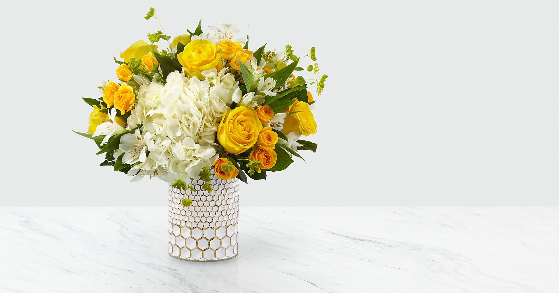 Bees Knees - The honeycomb designed vase filled with yellow and white garden flowers. 