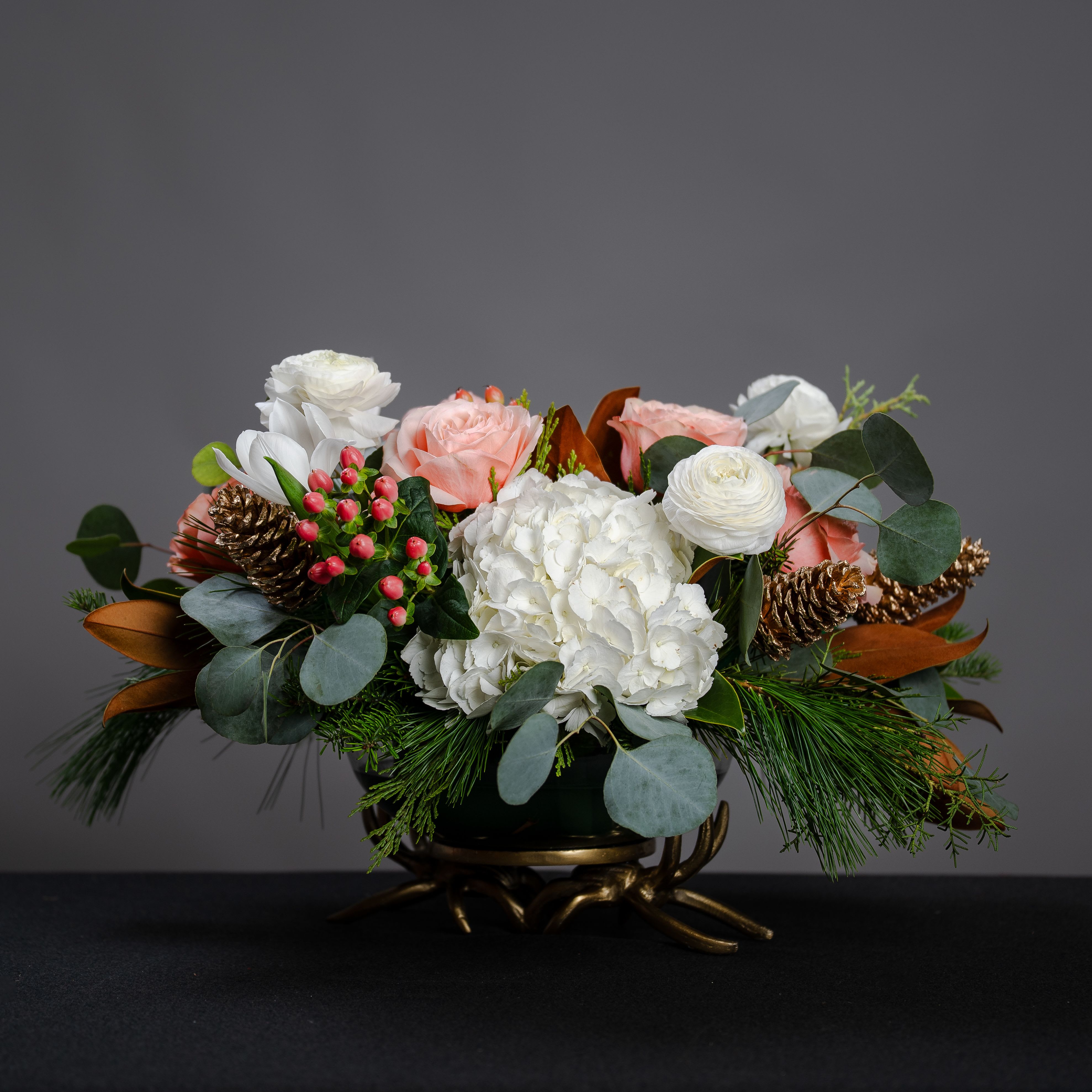 Brookside Holiday - This is a gorgeous piece set in a glass bowl that has a gold base resembling antlers. It is filled hydrangea, ranunculus, tulips, roses, hypericum berries, winter greenery, and pine cones.  It makes a lovely centerpiece or would look beautiful anywhere in the house. Approximate size, 22&quot; wide and 15&quot; tall. 