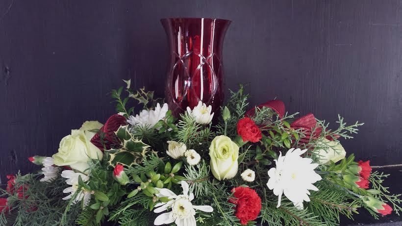Season's Glow Centerpeice - Surrounding a designer red cut glass hurricane candle holder with a single taper candle at the center, this exquisite holiday fresh flower arrangement will be the perfect way to help them deck the halls with holiday cheer, bringing joy and grace to all of their festivities.