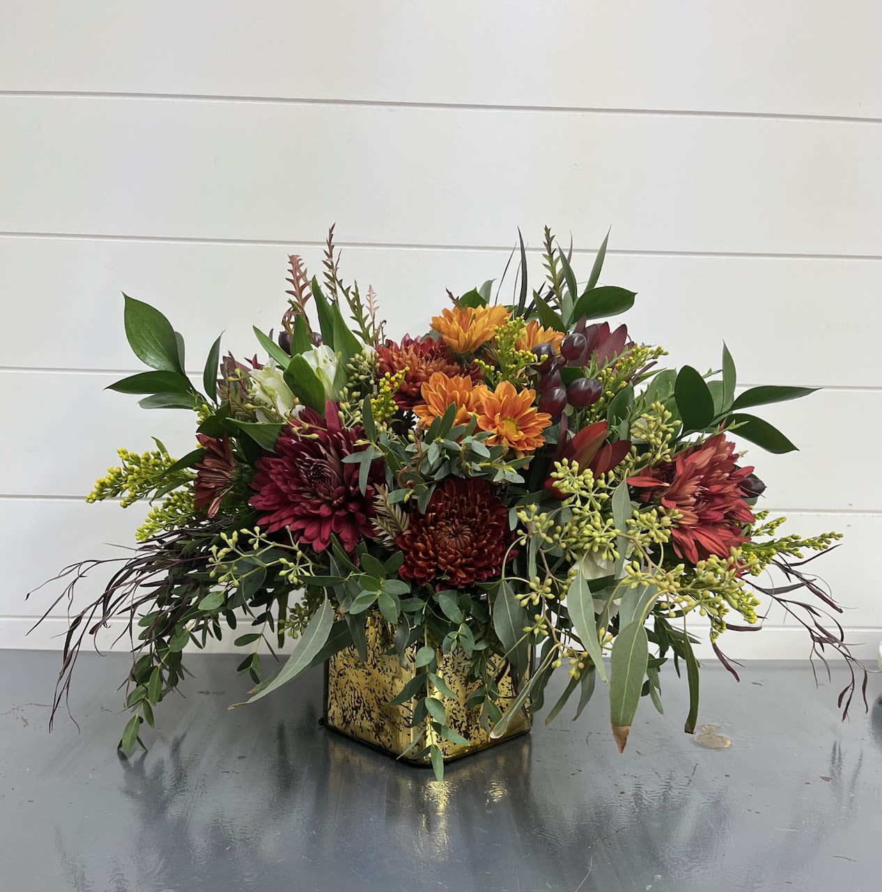 Golden Times Bouquet - Gathering around a table? Having friends over? This centerpiece is a modern take on a traditional piece... arranged in a gold cube container, the combination of rust, burgundy, white and yellow flowers is the perfect touch for any table or occasion. Not to mention the beautiful greenery that adds that little something.   Flowers and colors MAY VARY depending on availability. Local delivery only. 