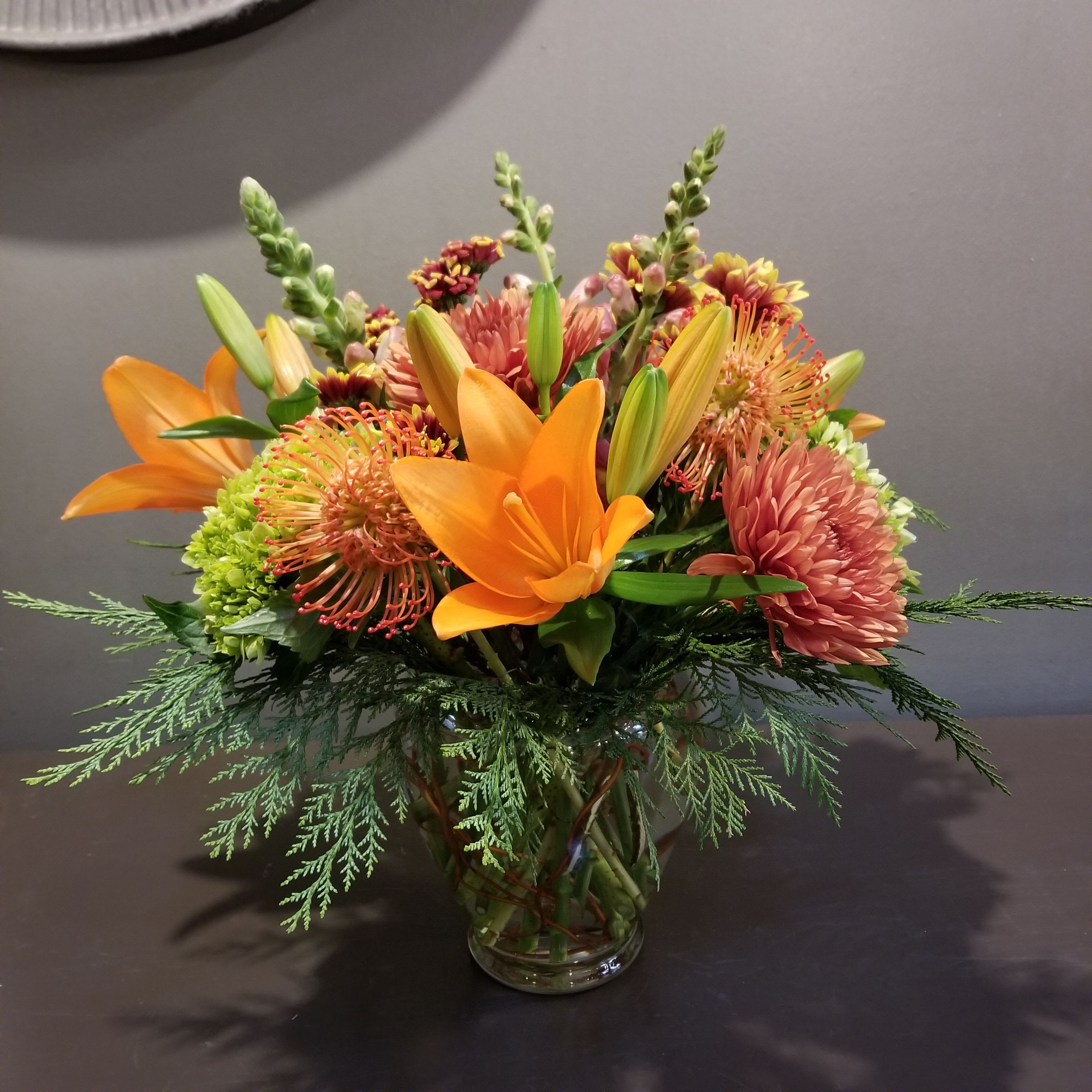 Autumn Whimsy - A whimsical bouquet in vibrant shades of autumn.  Measures approx. 18&quot;Tx18&quot;W and arrives in a glass vase.