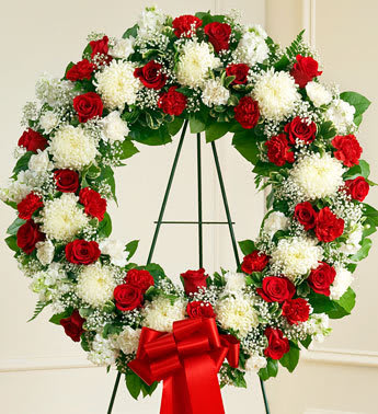 Serene Blessings Standing Wreath - Red &amp; White - This beautiful floral tribute shows your compassion, faith and love during this difficult time. This standing spray arrangement in the shape of a wreath is created from fresh mix roses, white football mums, spiral eucalyptus and more. Traditionally sent directly to the funeral home by family members or friends and displayed on a stand. 