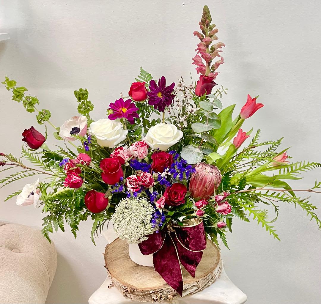 Burgundy Road - Product Information Theme Colors: Shades of burgundy with red and white  Featured Blooms: Roses, Protea, poppy anemone, tulips, Dahlia with Seasonal Blooms  HK Flowers have a uniqueness of florals and seasonal blooms, certain flowers or colors may not be available as each season affects the availability, color, size, and shape of each floral bloom. Some flowers may be substituted accordingly.  Photos are used as a reference for the color palette and is NOT indicated of the final product. We ask for your trust in us that we will pick out the best seasonal available blooms, while still capturing the arrangements' theme and colors mentioned above.