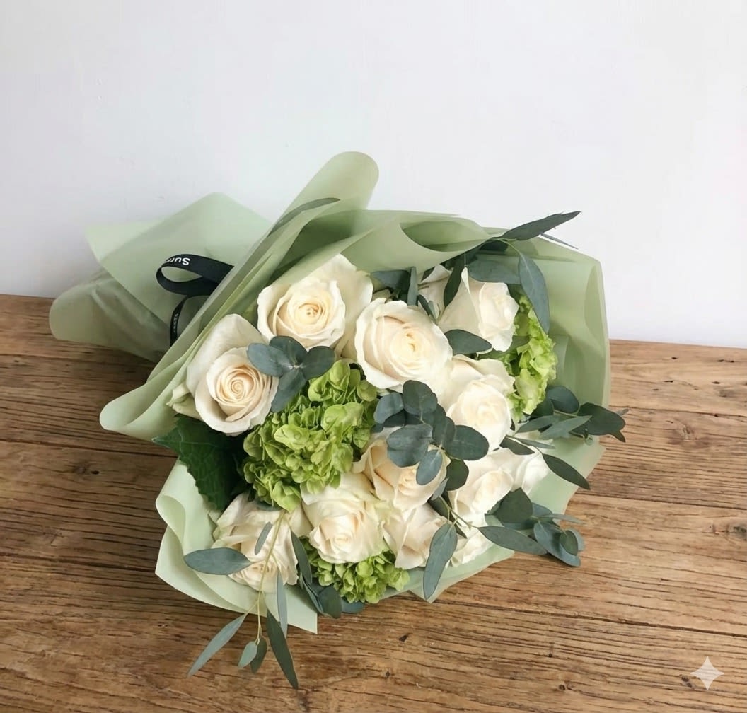 Dozen handtied white roses - For romantic occasions, this beautifully wrapped handtied bouquet of 12 elegant white roses is the perfect choice! The white roses are complemented by bright green hydrangea and flowy eucalyptus. The standard includes a dozen (12) white roses. Deluxe size includes two dozen (24) white roses. Premium includes three dozen white roses (36).