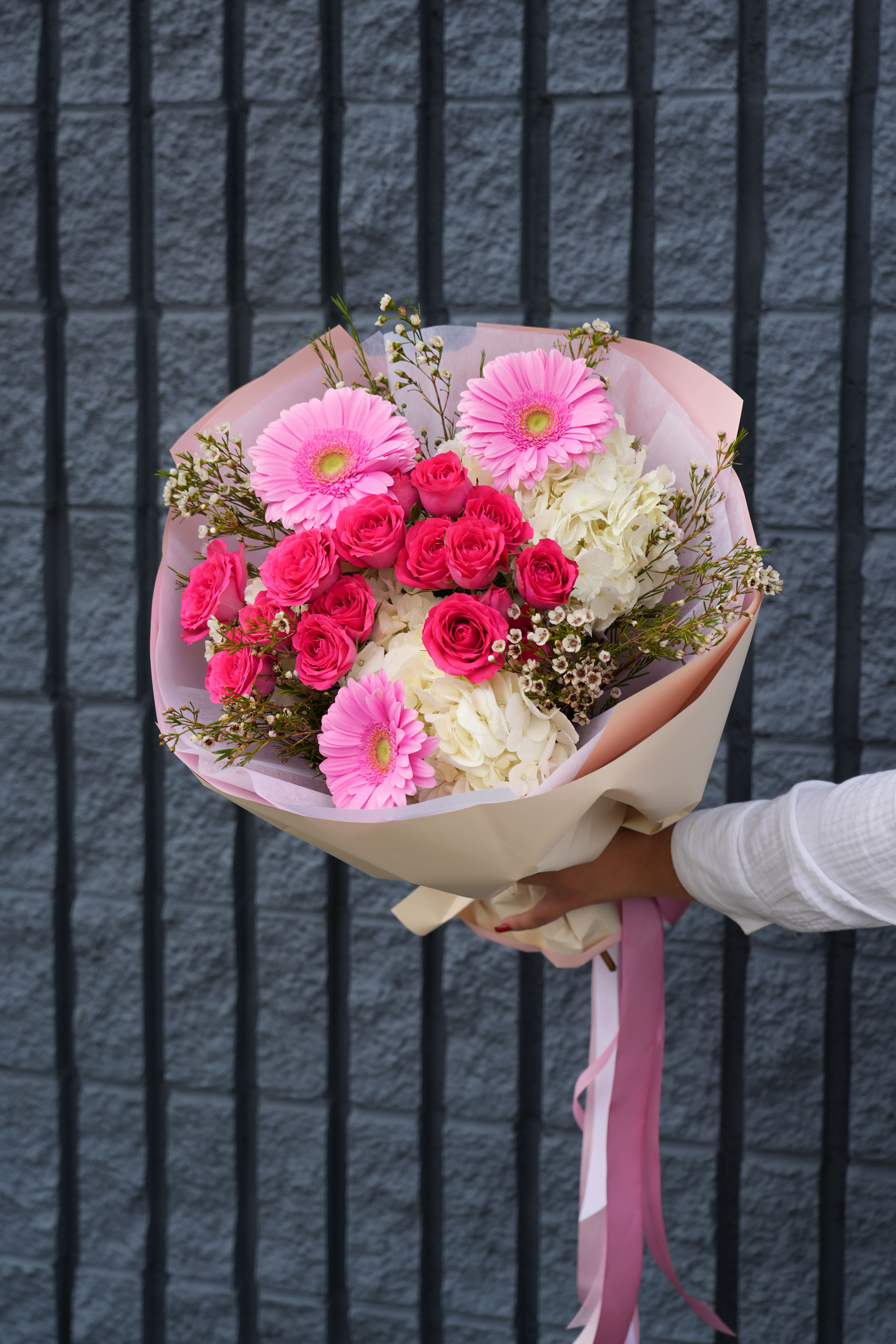 Pink Bliss Bouquet - Delight your senses with the enchanting Pink Bliss Bouquet, a stunning arrangement that perfectly captures the essence of elegance and joy. This exquisite bouquet features a vibrant blend of pink gerbera daisies, hot pink spray roses, and lush white hydrangeas, accented with delicate fillers and lush greenery. Wrapped in soft pink and cream paper, and tied with a matching ribbon, this bouquet is a true testament to beauty and sophistication. Whether you're celebrating a special occasion or simply brightening someone's day, the Pink Bliss Bouquet is sure to leave a lasting impression. 