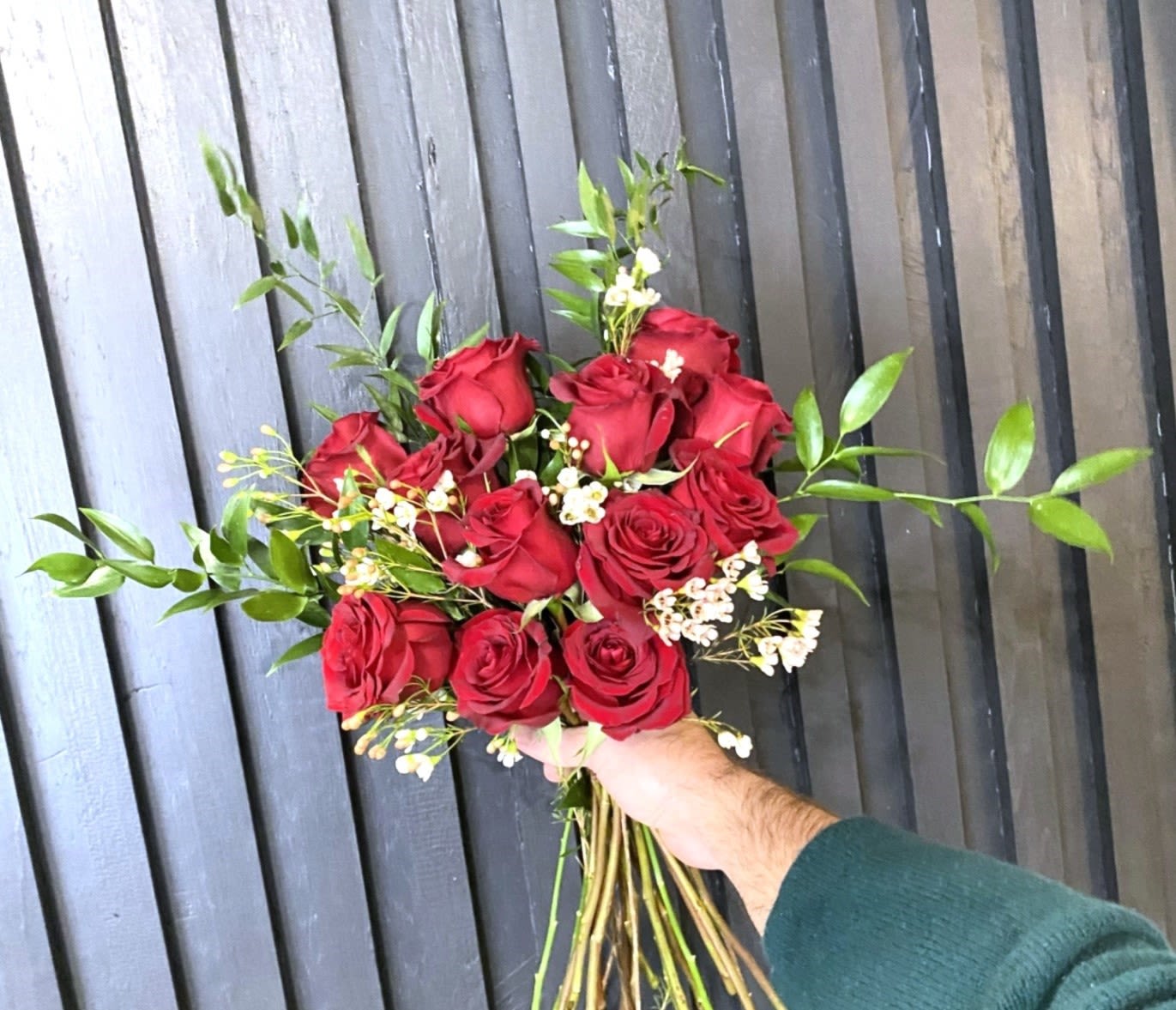 Handtied Dozen Red Roses - A bouquet of 12 long stemmed roses, in classic red, with sprigs of assorted greenery and Eucalyptus and a touch of Wax Flower filler. Wrapped in kraft paper and tied with silk ribbon. 