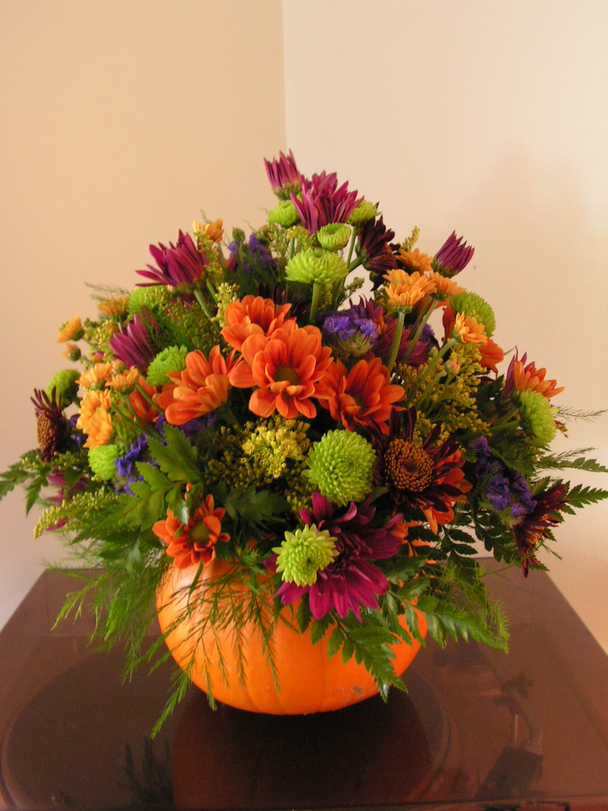 Fresh Pumpkin Centerpiece - A fresh pumpkin from our local growers stuffed full of beautiful fall mums, statice, and solidago. Brightens any ones day and makes a wonderful hostess gift for the holidays. 