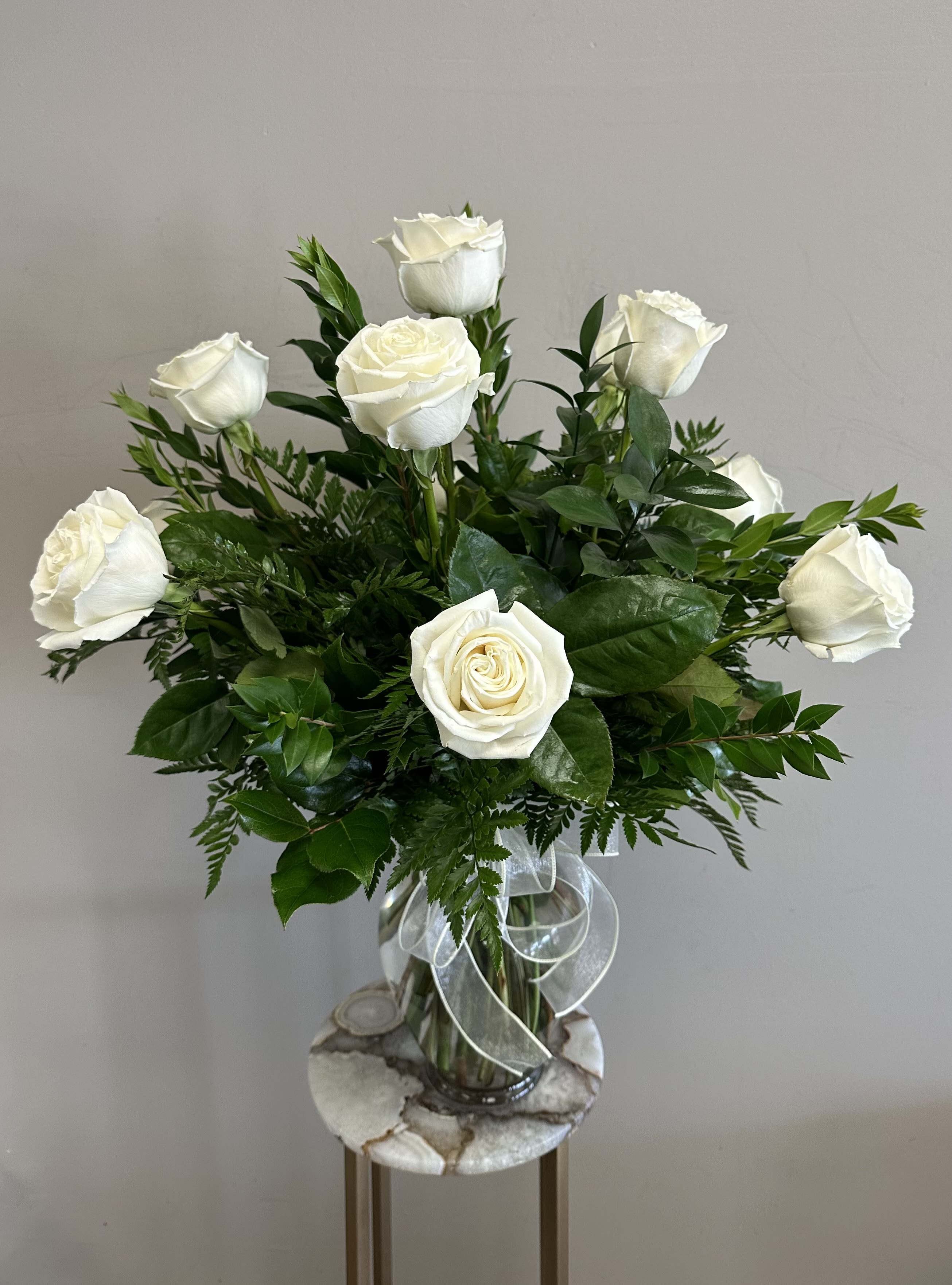 Dozen Long Stem White Roses - A dozen long stem white roses with assorted greenery in a clear glass vase. These roses are the perfect gift for anniversaries, birthdays, retirement, or even just because! Order for a same day or next day delivery and give us a call if you want custom flowers. 