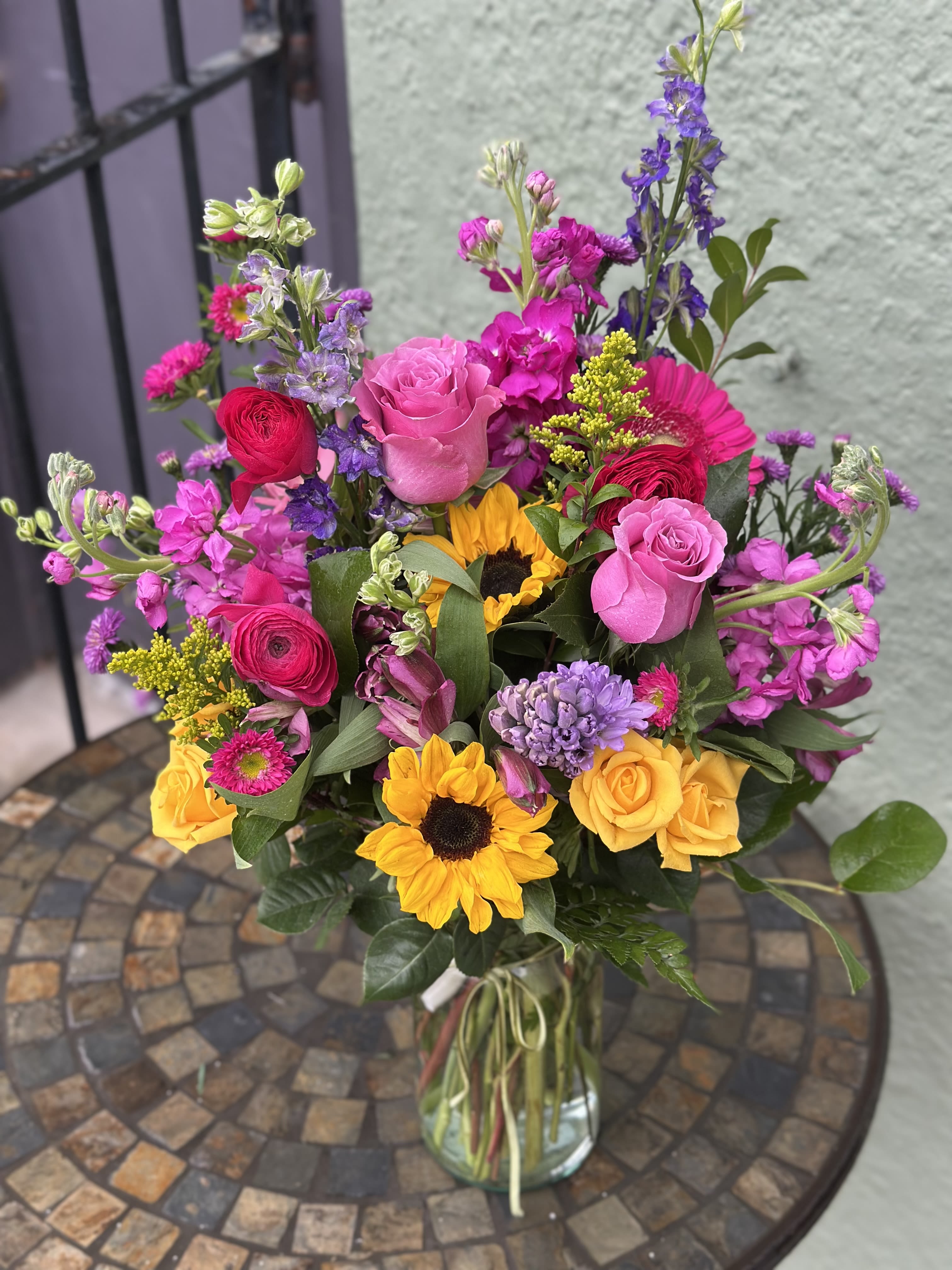 Sweet on You - Beautiful happy flowers in array of bright colors, featuring mini sunflowers, larkspur, ranunculus, rose, stock, hyacinth and more!