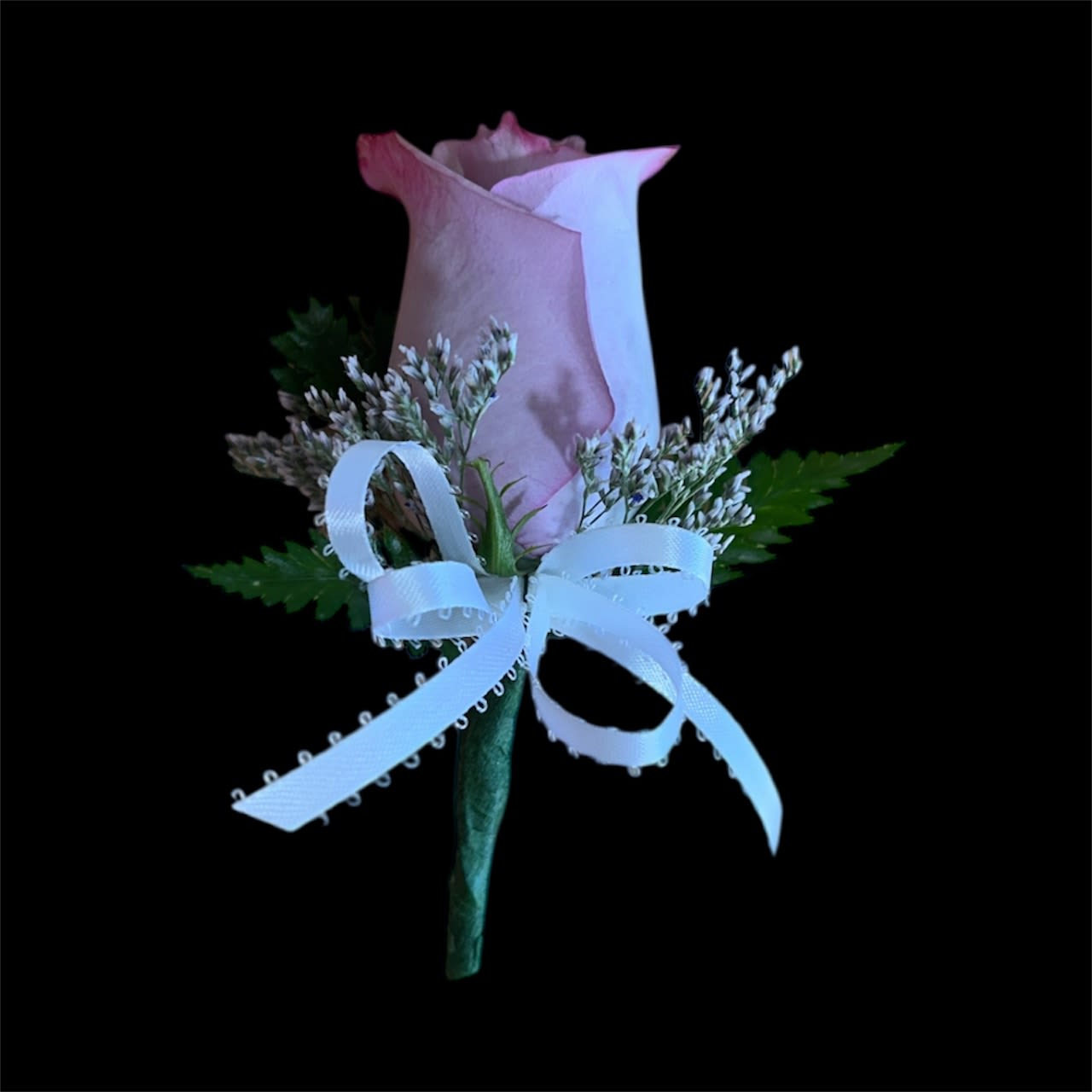Soft Lavender Boutonniere - A single lavender rose accented with soft limonium and tied with a crisp white ribbon. This delicate and elegant boutonniere adds a touch of romance and charm—perfect for weddings, proms, and special occasions.