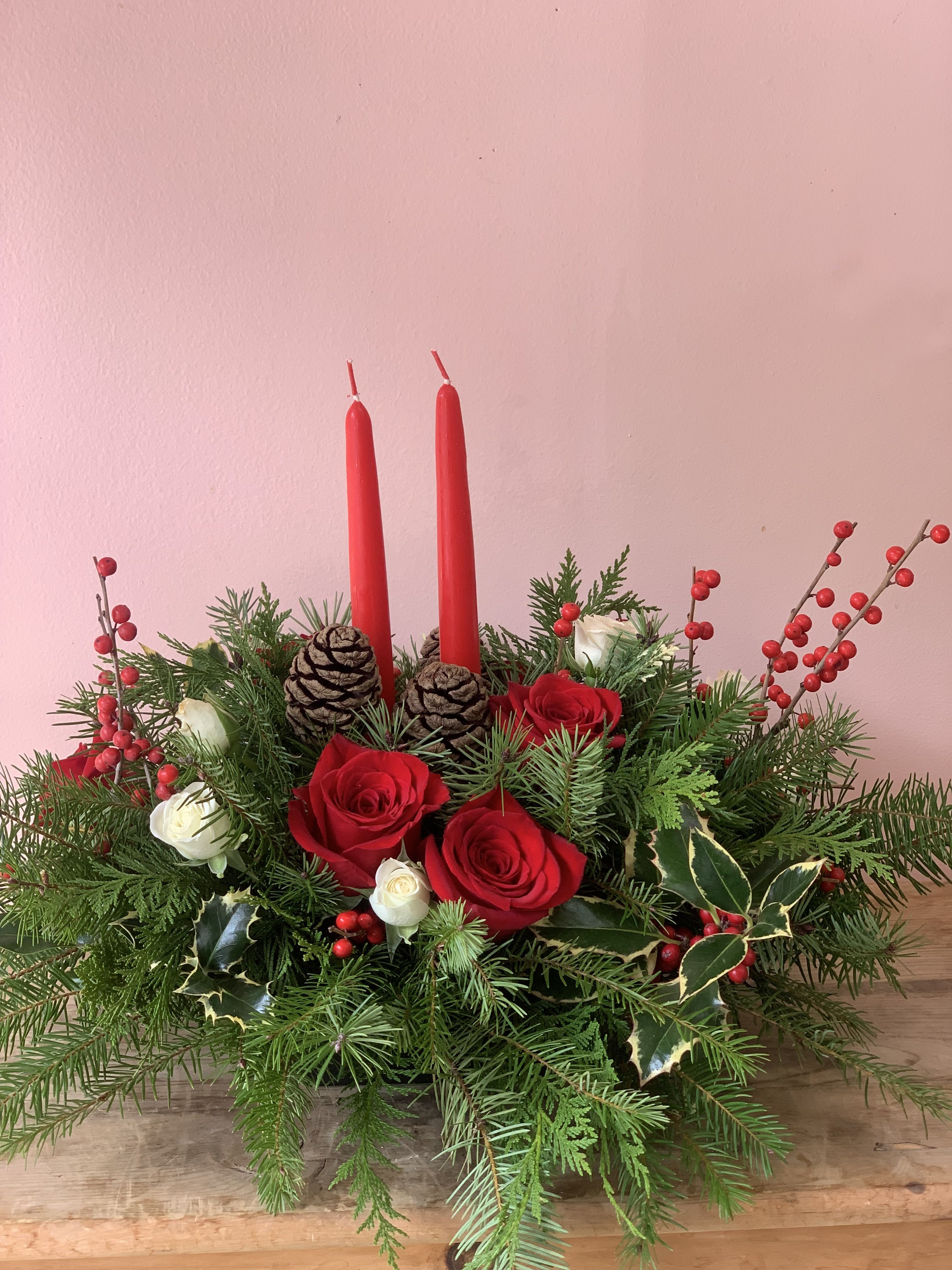 Christmas Centerpiece Flowers by Fillmore Florist San Francisco - Complete your dinning room table this Christmas with a beautiful fresh flowers centerpiece from Fillmore Florist in San Francisco. Christmas Centerpiece Flowers is made with all of the essential Christmas flowers and greens. Made with red Roses, white spray Roses, Holy, decorative pine cones and two red candlesticks, Christmas Centerpiece Flowers is the perfect finishing touches decoration for your Christmas this year. Let Fillmore Florist in San Francisco help decorate your dinning room table this Christmas. Serving flowers to pacific heights in San Francisco for over 25 years. Flower delivery in San Francisco has never been easier than with Fillmore Florist San Francisco. Place your order online at anytime or call us directly to place your floral orders.  Reliable florist in San Francisco.  Approximate Dimensions: 12” H x 12” W