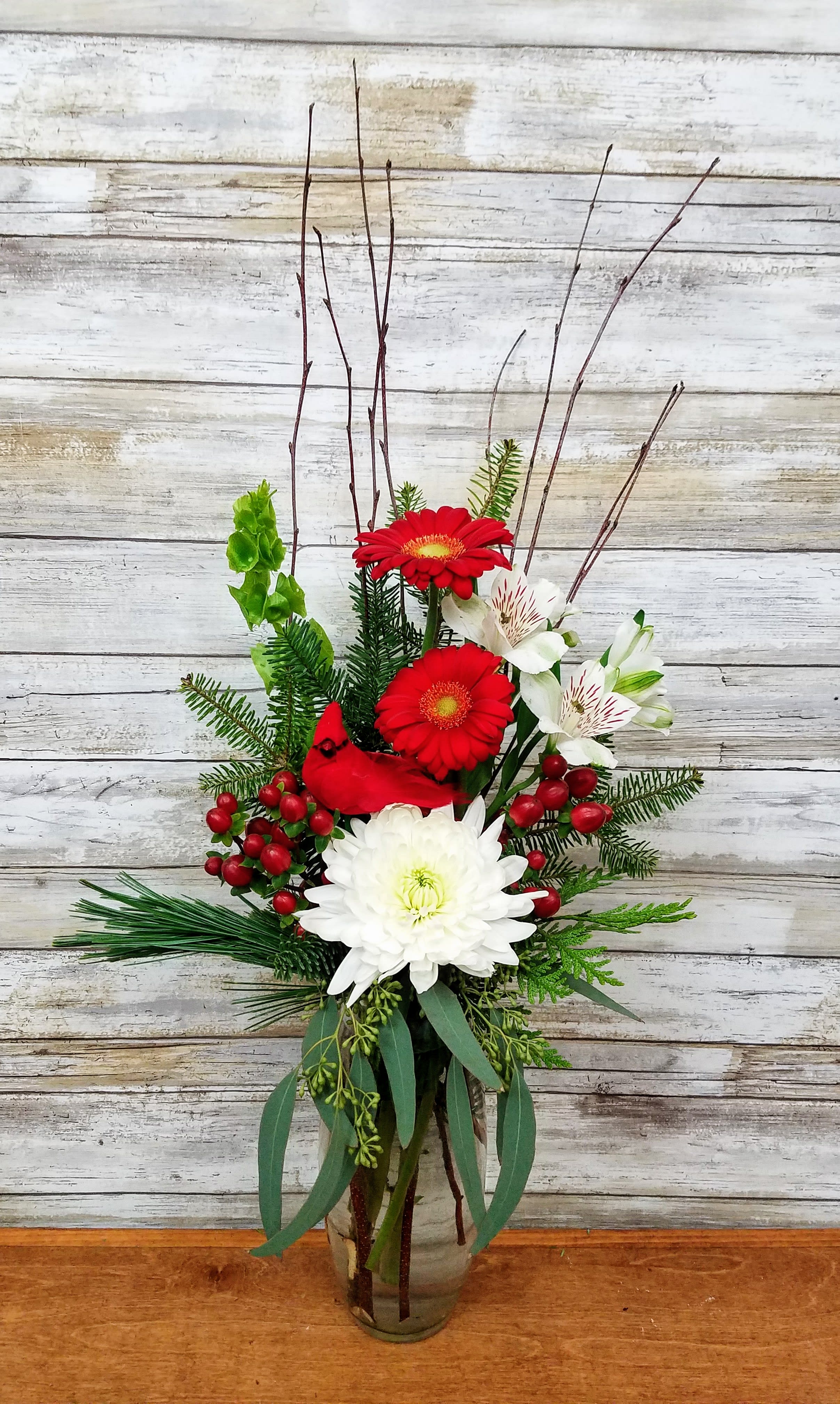 Holiday Splendor - Send warm wishes this holiday season with a festive mix of holiday flowers accented with holiday greens and a perched cardinal.   Approximately 24&quot; Tall 