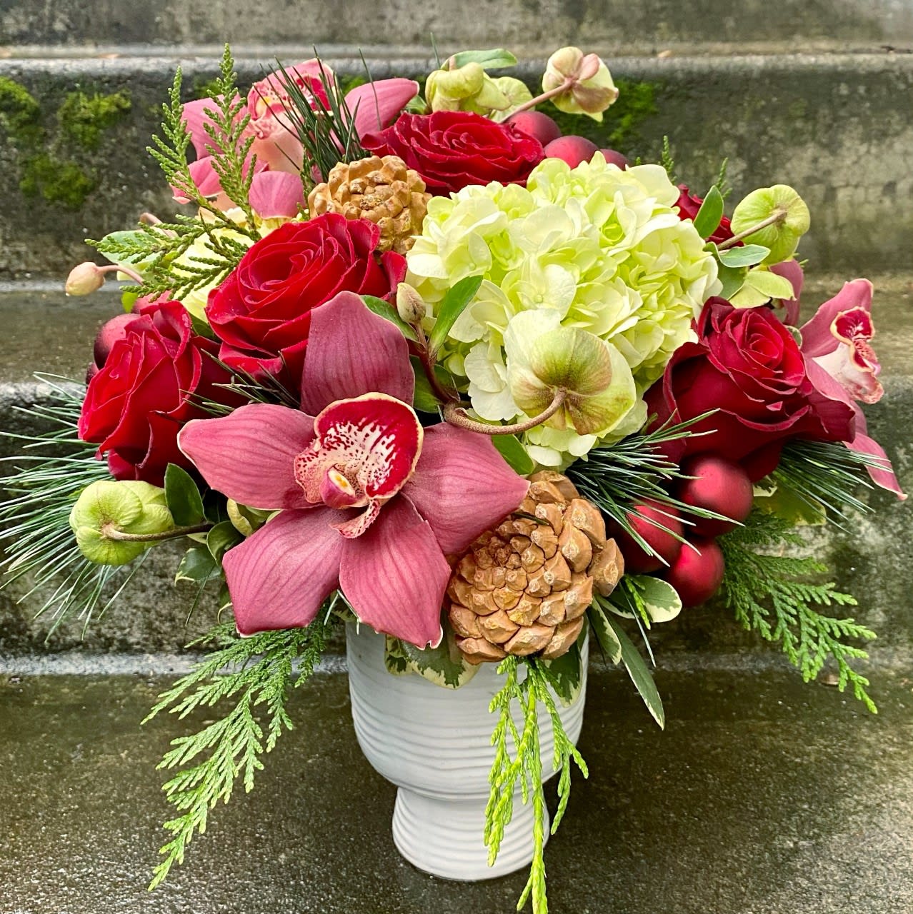 Happy Holidays - Available beginning December 3rd.  Send your best holiday wishes with a custom Christmas arrangement. We will create a beautiful floral for you with hydrangeas and premium flowers accented with evergreens and glass ornaments, pine cones or pinon cones for a look that is sure to make the recipient's day merry and bright.   Approximate dimensions: 9 inches tall by 8 inches wide  Orders for this Fiori Floral Design original arrangement for delivery outside of our delivery area will be filled by another florist.  We will work closely with them to create something that has a similar feeling to our arrangement, but what they create may not match our photographs because every florist carries different items. They may need to substitute the vase, flowers used or greenery.                                                                                                                                                                                                                                                                                                                                                                                          