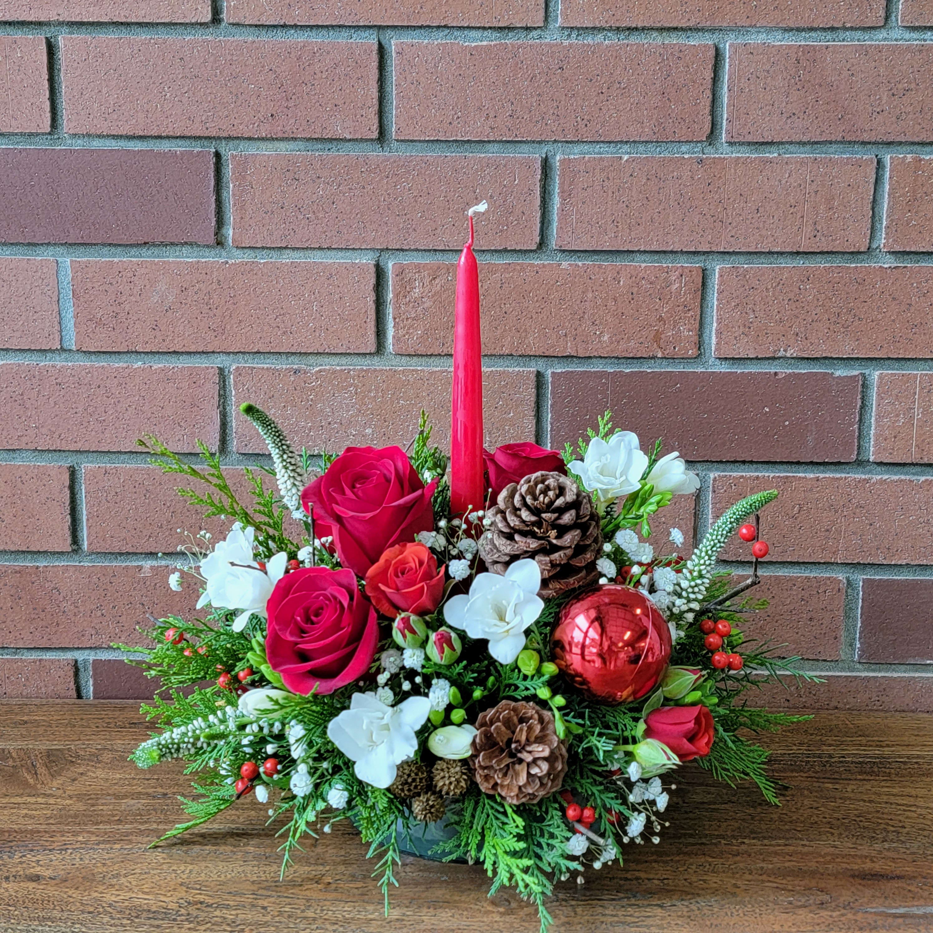 Fragrant Christmas Centerpiece  - White fragrant freesia, red spray roses, veronica, christmas evergreens, roses, spray roses and pine cones accented with red berries. Designed all around