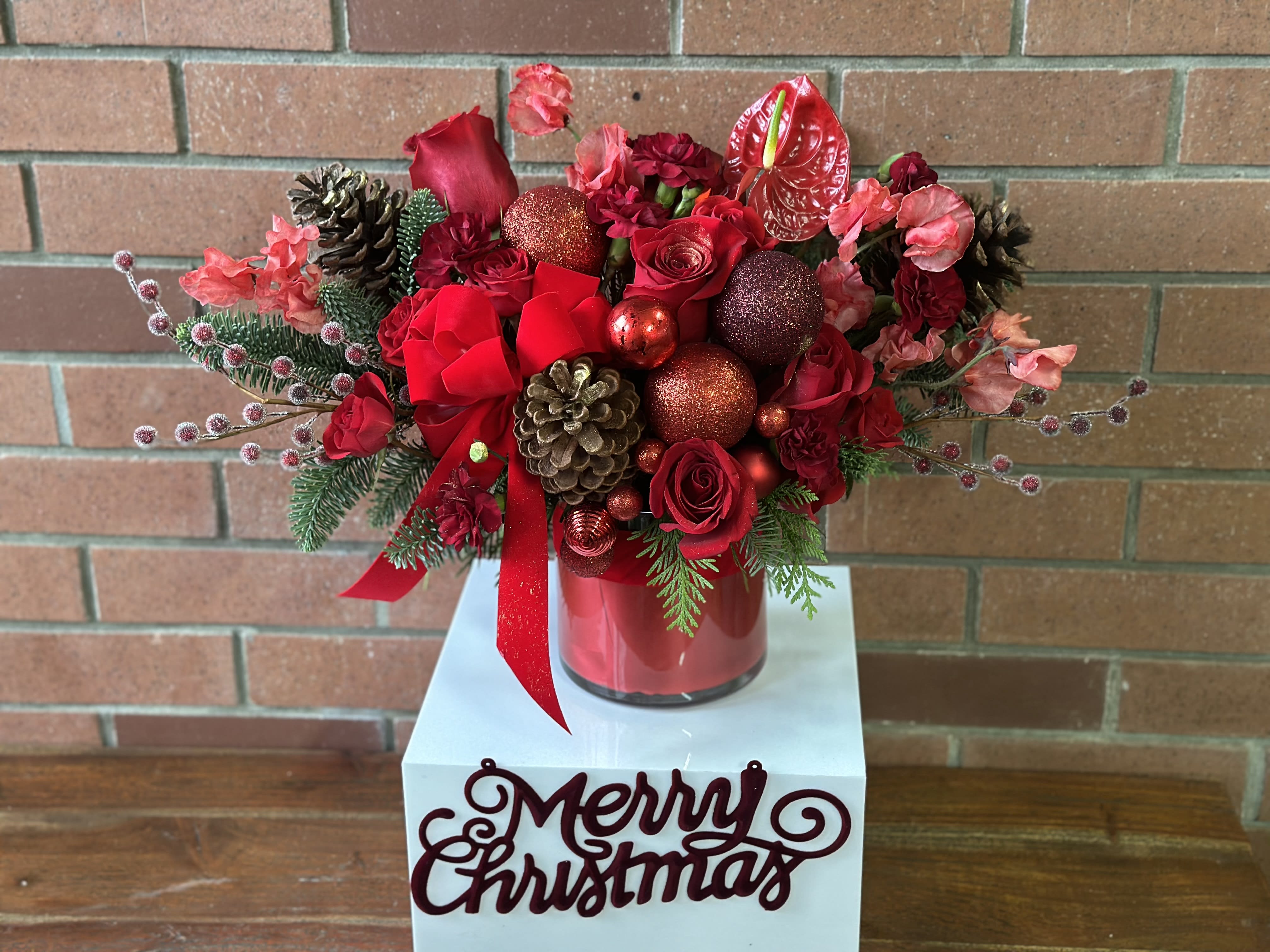 Merry Christmas Bouquet  - Enjoy the holidays and brighten the holiday season with our gorgeous “Merry Christmas Bouquet”  This fresh arrangement includes red roses, spray roses, burgundy mini carnations, red sweet pea, red anthurium, pine cones and ornaments with a beautiful red velvet ribbon. 