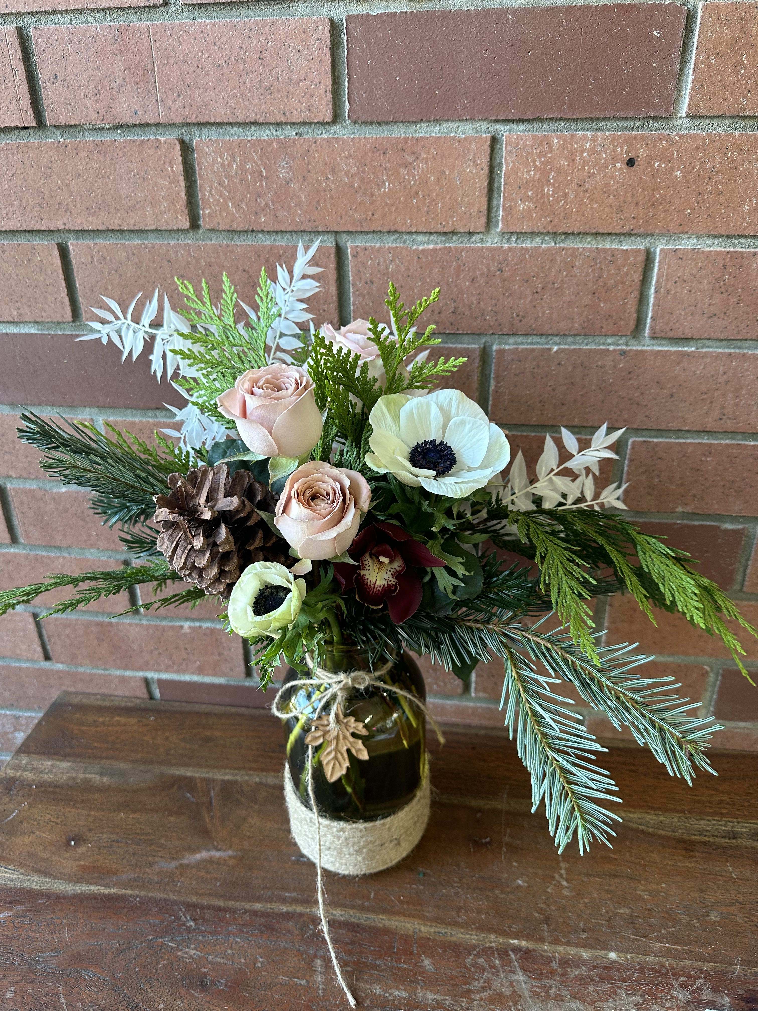 Winter Love Bouquet  - Lovely winter selection of mixed evergreens, gorgeous cappuccino roses anemones pine cones and a red orchid in a green bottle jar accented with a leaf 