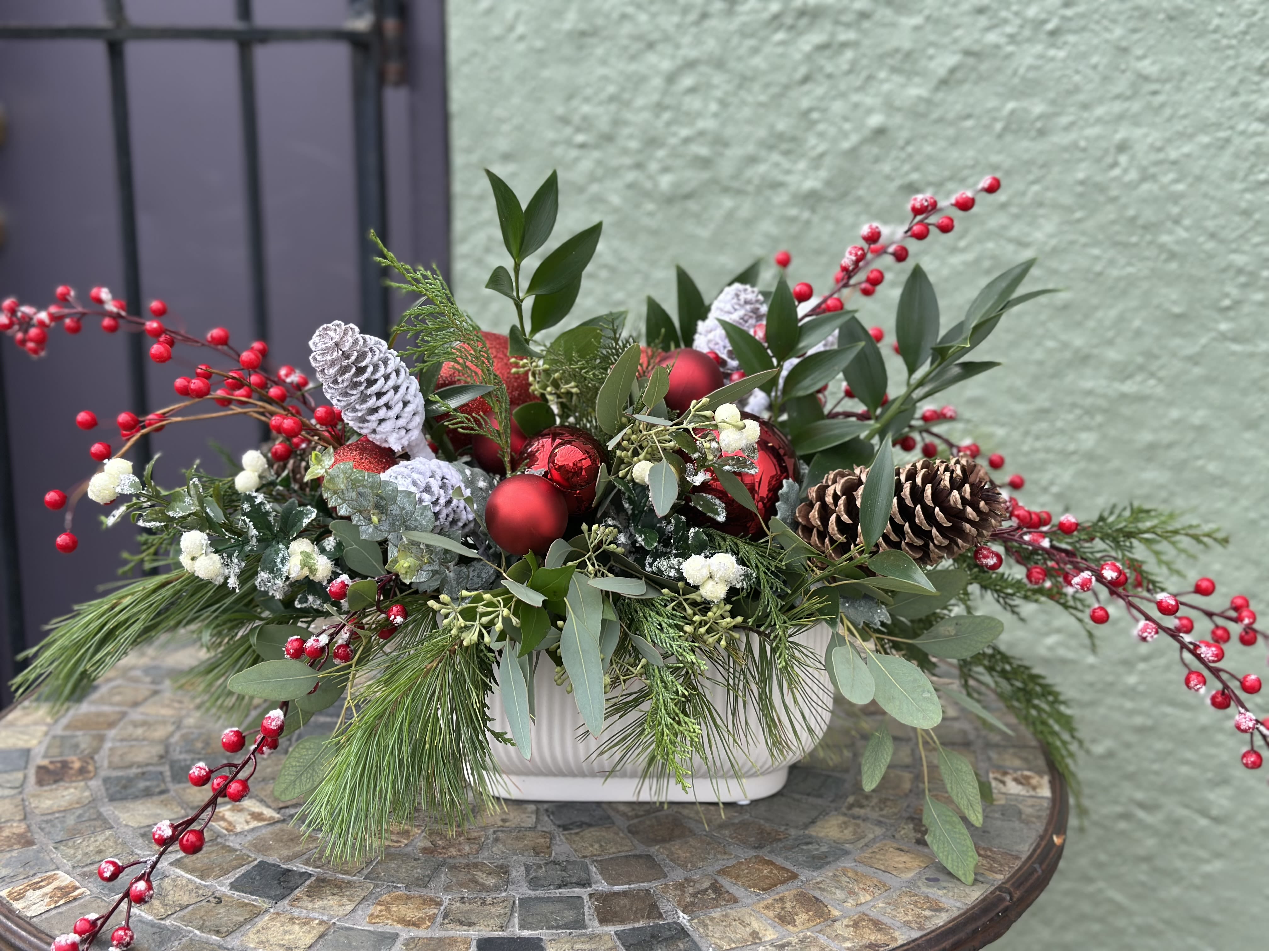 Dumbarton Centerpiece - Bring holiday magic to home! This low profile centerpiece is designed in an elegant white ceramic and filled with the season's fragrant evergreens and eucalyptus. Accented with glowing red ornaments and faux berries, it will brighten your home with holiday spirit for a long time. Great holiday gift idea!