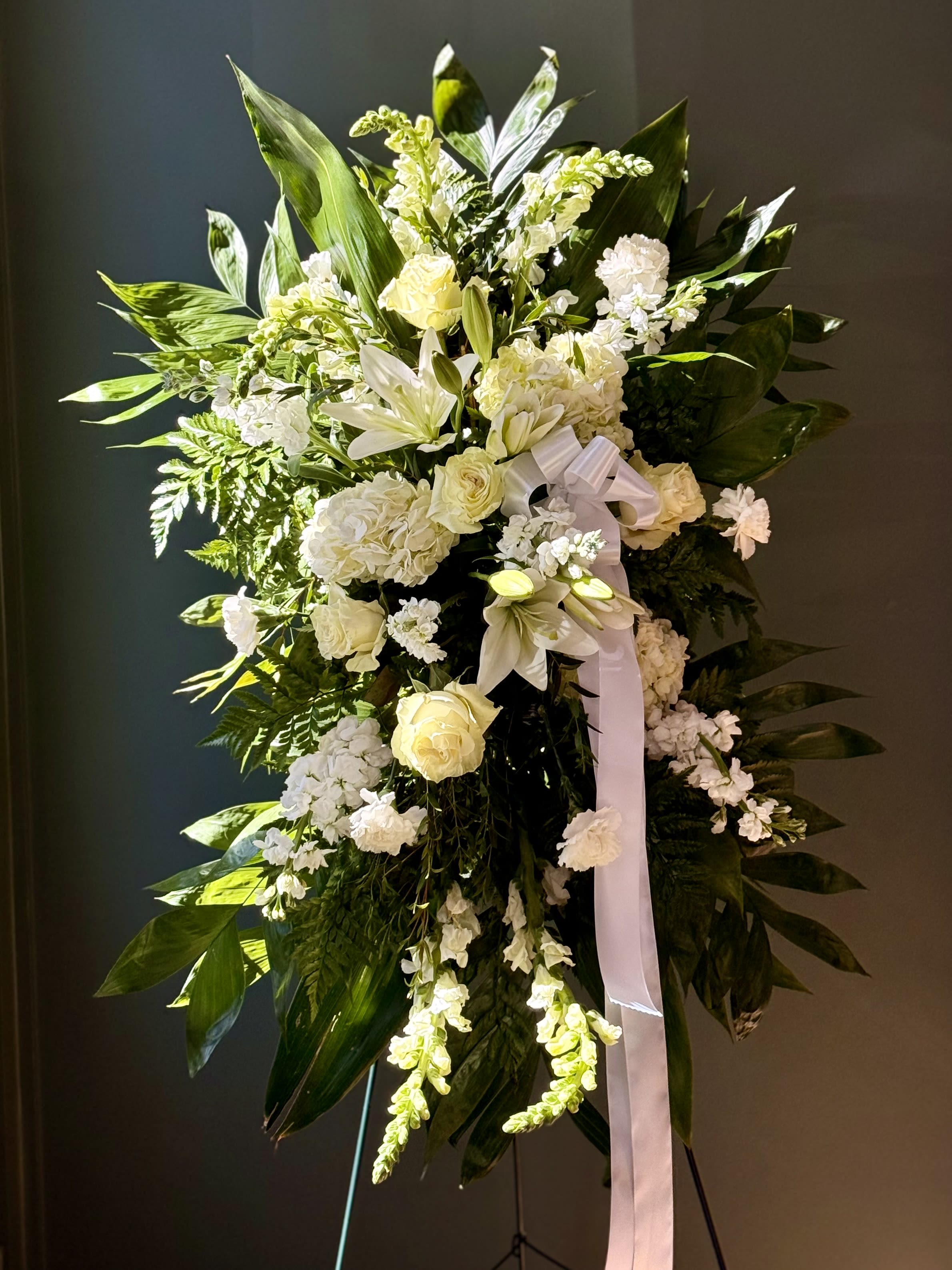 True Sympathy by BloomNation™ - An all white tribute, this funeral spray is pure and tranquil. Featuring a variety of white flowers and green palms this elegant funeral spray brings a feeling of peace to it's surroundings 