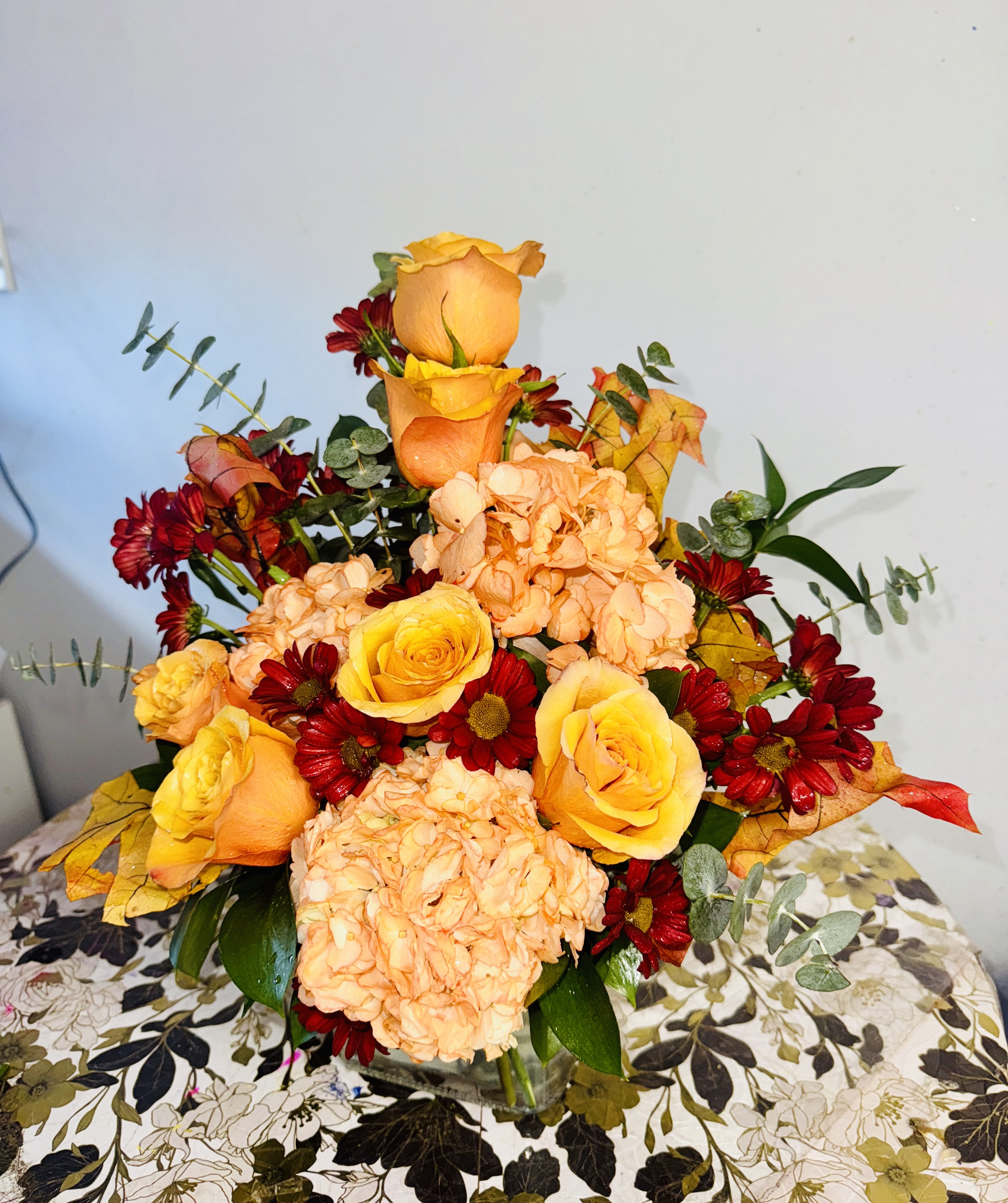 Golden Gratitude - A bouquet that whispers elegance and gratitude. Yellow roses, orange hydrangeas, and burgundy chrysanthemums mingle with fresh eucalyptus in a design that celebrates autumn’s beauty. Perfect for gifting warmth and tenderness this Thanksgiving season.