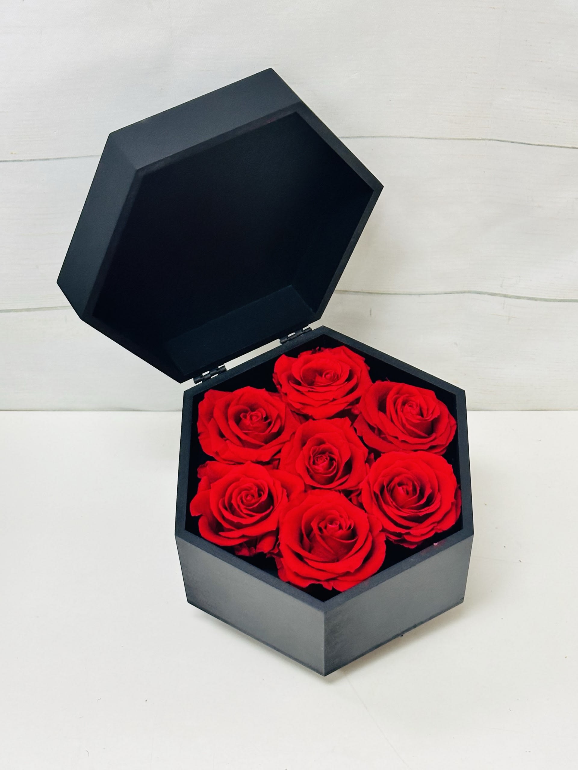Real Preserved Roses Rotating Hexagon Box (7 Roses) - Enjoy our incredible new preserved roses! With patented technology, these stunning roses are designed to last up to a year, allowing you to appreciate their beauty for an extended period. This particular product features 7 timeless Red roses.  Key Features:  Long-Lasting Beauty: Using advanced patented technology, this preserved red rose maintains its natural appearance and vibrant color for up to a year.  Elegant Design: The classic red rose symbolizes love and admiration, making it a perfect gift or decorative piece.  Low Maintenance: No watering or special care required, simply enjoy the beauty of the rose for an entire year.  Versatile Use: Ideal for home decor, office spaces, special occasions, or as a thoughtful gift for loved ones.  High-Quality Preservation: Ensures the rose retains its natural softness, shape, and color, providing a realistic and lasting impression.  Experience the timeless elegance of our Preserved Red Rose, a perfect blend of natural beauty and innovative technology that brings joy and sophistication to any setting.