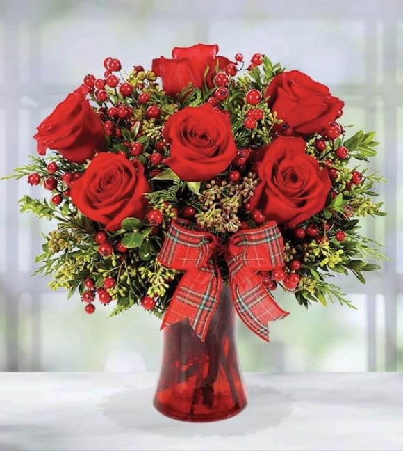 Holiday Kisses - Feel the holiday spirit with our Holiday Kisses Bouquet! Adorned with bold red roses, red berries and winter greens, this festive arrangement creates a picturesque season's greetings! Bow design may vary.  Item pictured is a depiction of an arrangement that we will make as similar as possible with the same look and feel.