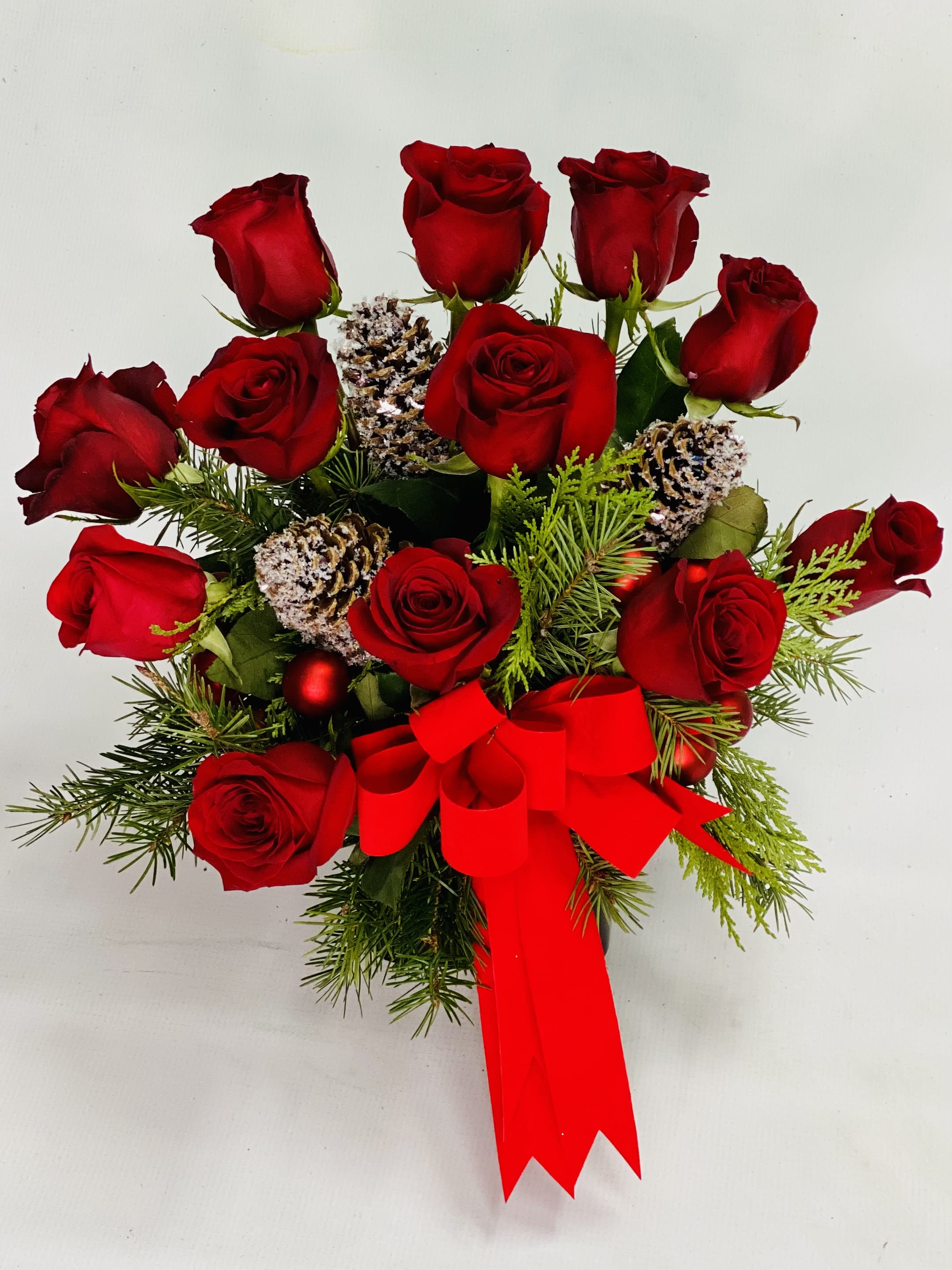 Santa baby Roses - Santa baby really loves me 12 red roses arranged in a beautiful red cube adorned with mix winter greens pinecones and a red velvet bow