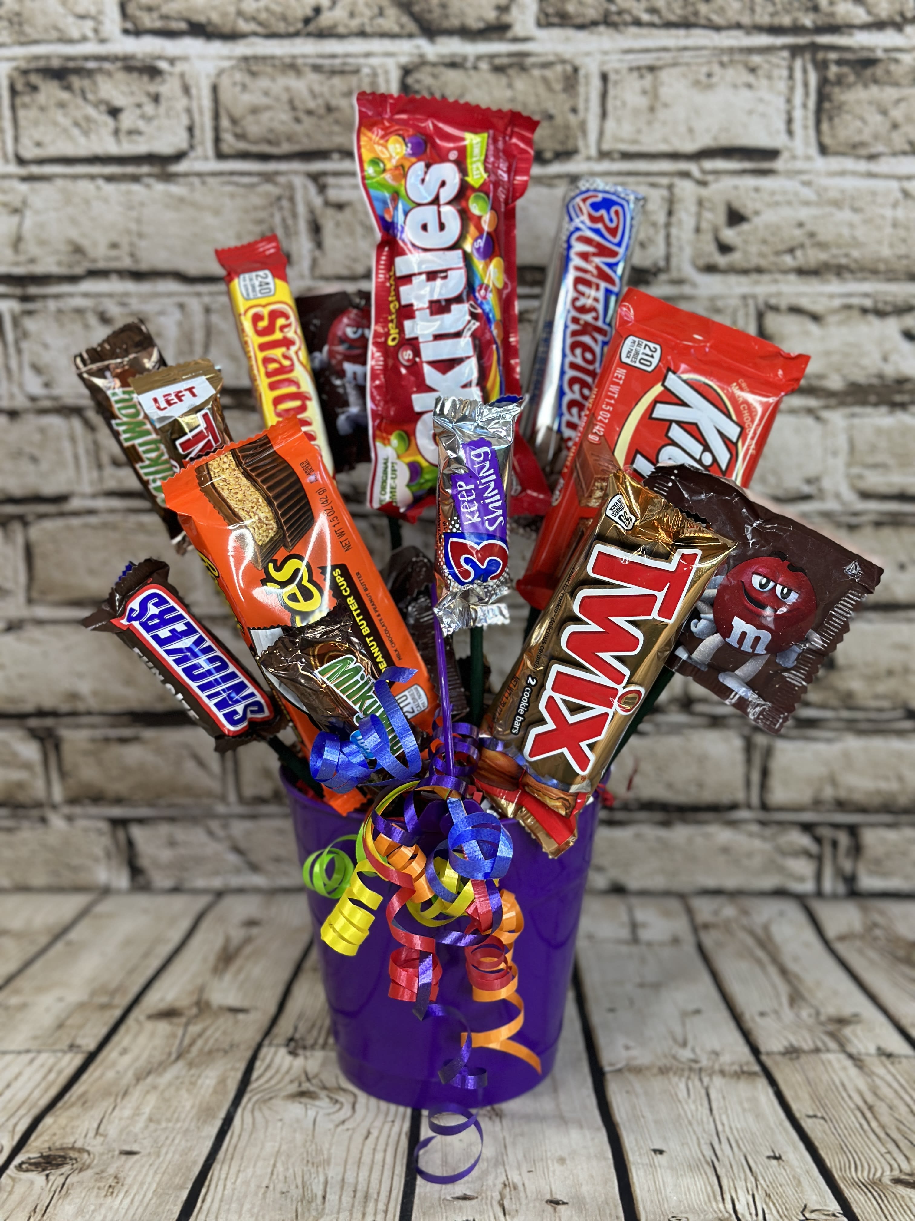Candy Bouquet - Classic - This delightful candy bouquet is a playful fusion of color and sweetness, featuring an assortment of vibrant candies and treats artfully arranged in a whimsical bouquet design. Each candy bouquet creates a fun and festive display that’s perfect for birthdays, celebrations, or simply to brighten someone's day. It’s a delightful treat for the eyes and the taste buds!   Approximately 15 pieces per bouquet. Candy varieties may vary from photo depending on availability.  Candy Bouquet will be delivered wrapped in clear cellophane and ribbon to add that finishing touch