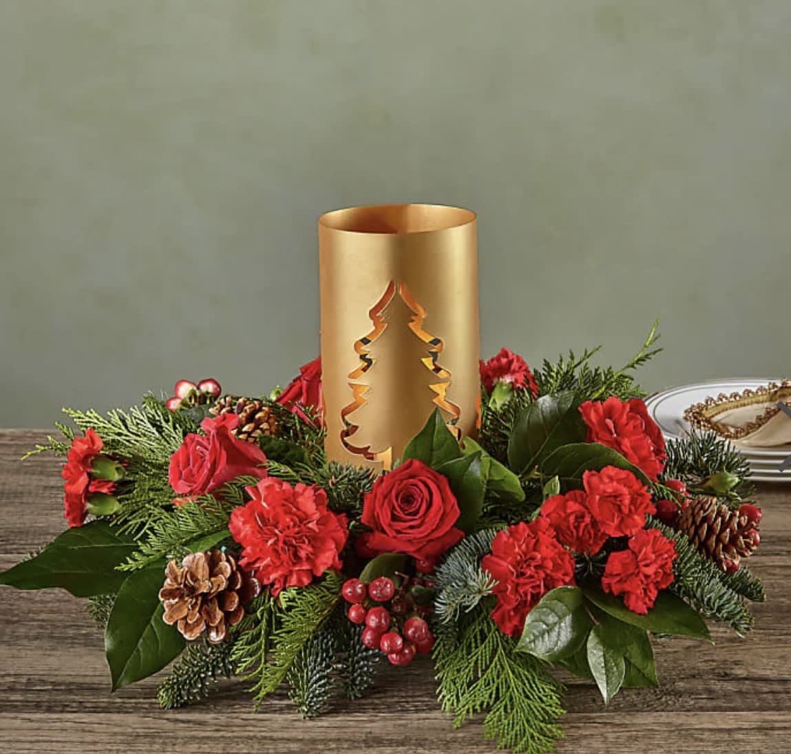 Evergreen Glow Centerpiece f - Add blustery cheer to any holiday table with this coniferous centerpiece studded with cardinal–red flowers and berries gathered around a glowing candlelit tree lantern. 
