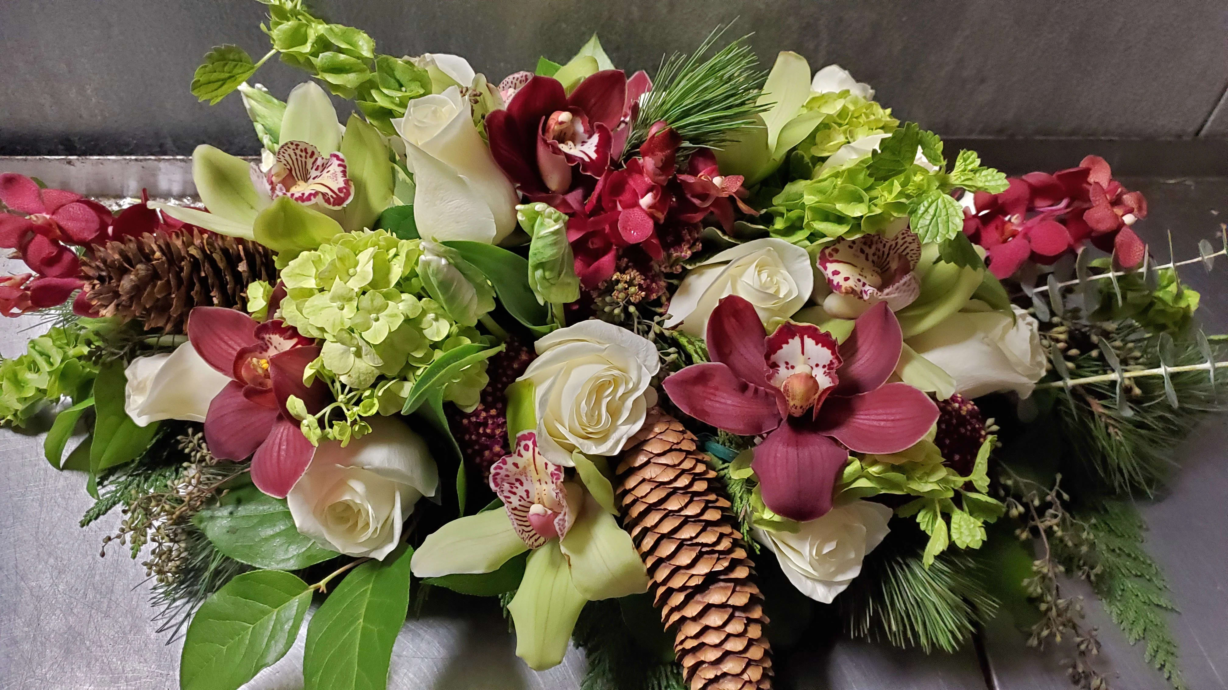 Back Bay Centerpiece - Back Bay Centerpiece. Burgundy and green are classic colors during this season, and they shine beautifully in this centerpiece  arrangement.  White roses are rimmed with mini green hydrangea, burgundy and green  orchids and a variety of winter greens that add the perfect touch of texture.