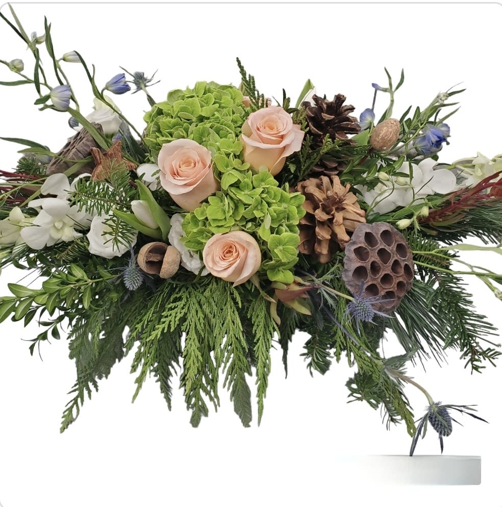 Winter Solstice - By far our most textured arrangement this season, Winter Solstice plays on the contrast between light and dark elements. Peach shimmer roses, green hydrangea, thistle and forest green foliage fade into dazzling sky blue delphinium, snowy white tulips, and white dendrobium orchids orchids. Ideal size for a kitchen table or island, coffee table or entry-way.