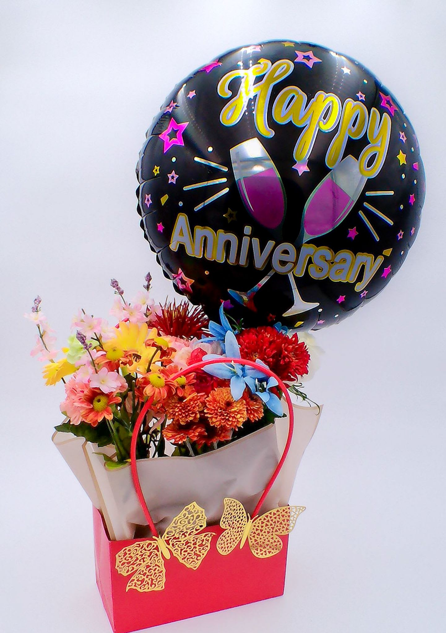 &quot;Happy Anniversary&quot; Flower Gift Bag with Butterflies - Mixed Fresh Flowers (14–16 stems): a colorful blend of 6 carnations, 2 roses, 2 chrysanthemums, 2 daisies, and 2 lilies. 18-inch Happy Birthday Foil Balloon (1 pc) Decorative Golden Butterfly (2 pc) Reusable Gift Bag (32.5cm*22cm*13cm) Total Weight:700 g Ideal for: Wedding anniversaries, Couple celebrations, or milestone anniversaries, Engagement or vow renewal celebrations.