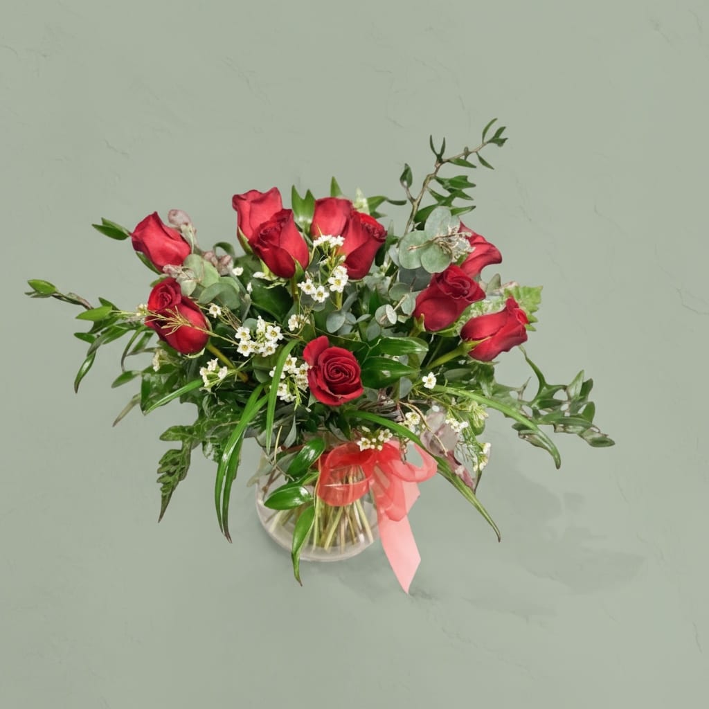 A Dozen Dreams - 12 Red roses accented with premium greens in a  clear vase. The perfect gift for anniversary or Valentine’s Day. Thanks for shopping local!