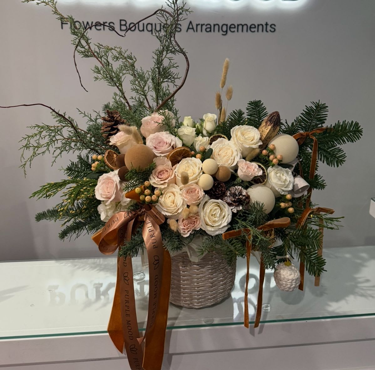 Gingerbread Vase - Embrace the warmth of the holiday season with our exquisite Gingerbread Vase. This handcrafted arrangement features a delightful mix of: 	•	Soft blush and cream roses 	•	Festive evergreens 	•	Elegant natural accents like pinecones and dried fruits 	•	Luxurious velvet ribbons for a seasonal touch  Perfect as a centerpiece, gift, or festive décor to elevate any space.  