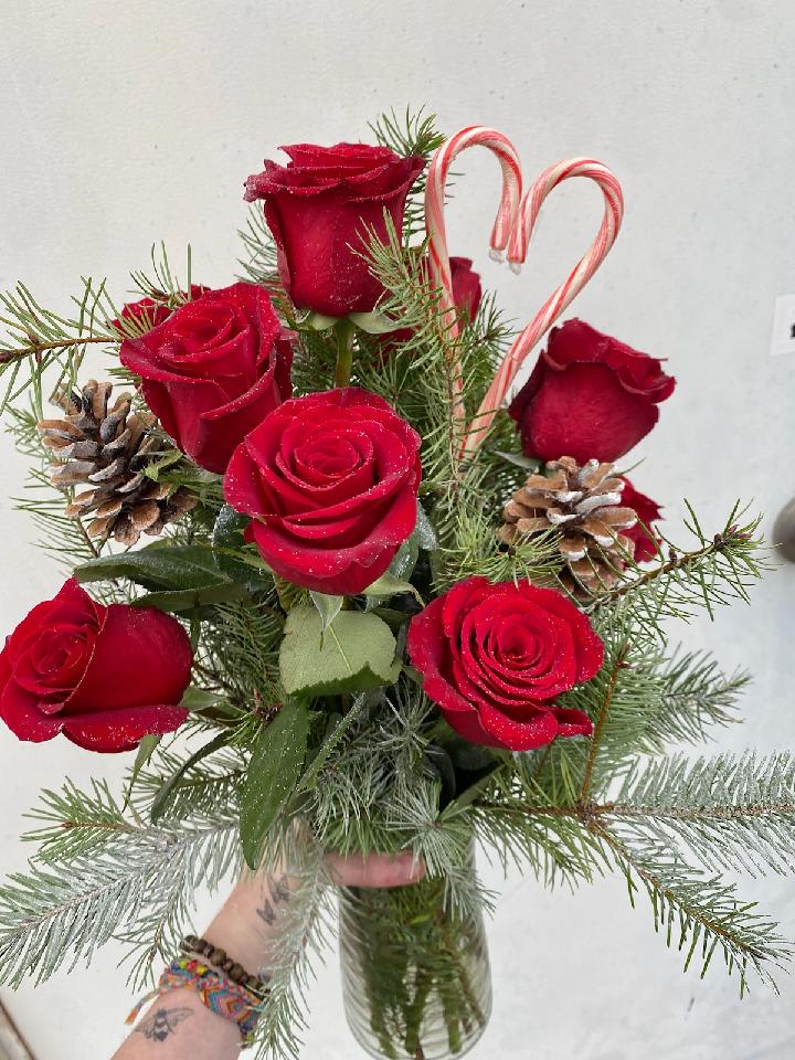 Cupids Crush - A festive holiday version of our classic dozen roses. Assorted pine and candy canes are sure to put you on the nice list this holiday!  Just to let you know, flowers and vases may vary but we do our best to match the arrangement shown.  Colors can vary from red, white, peach, shades of pinks, and yellows! If you have a preference let us know in the special instructions!