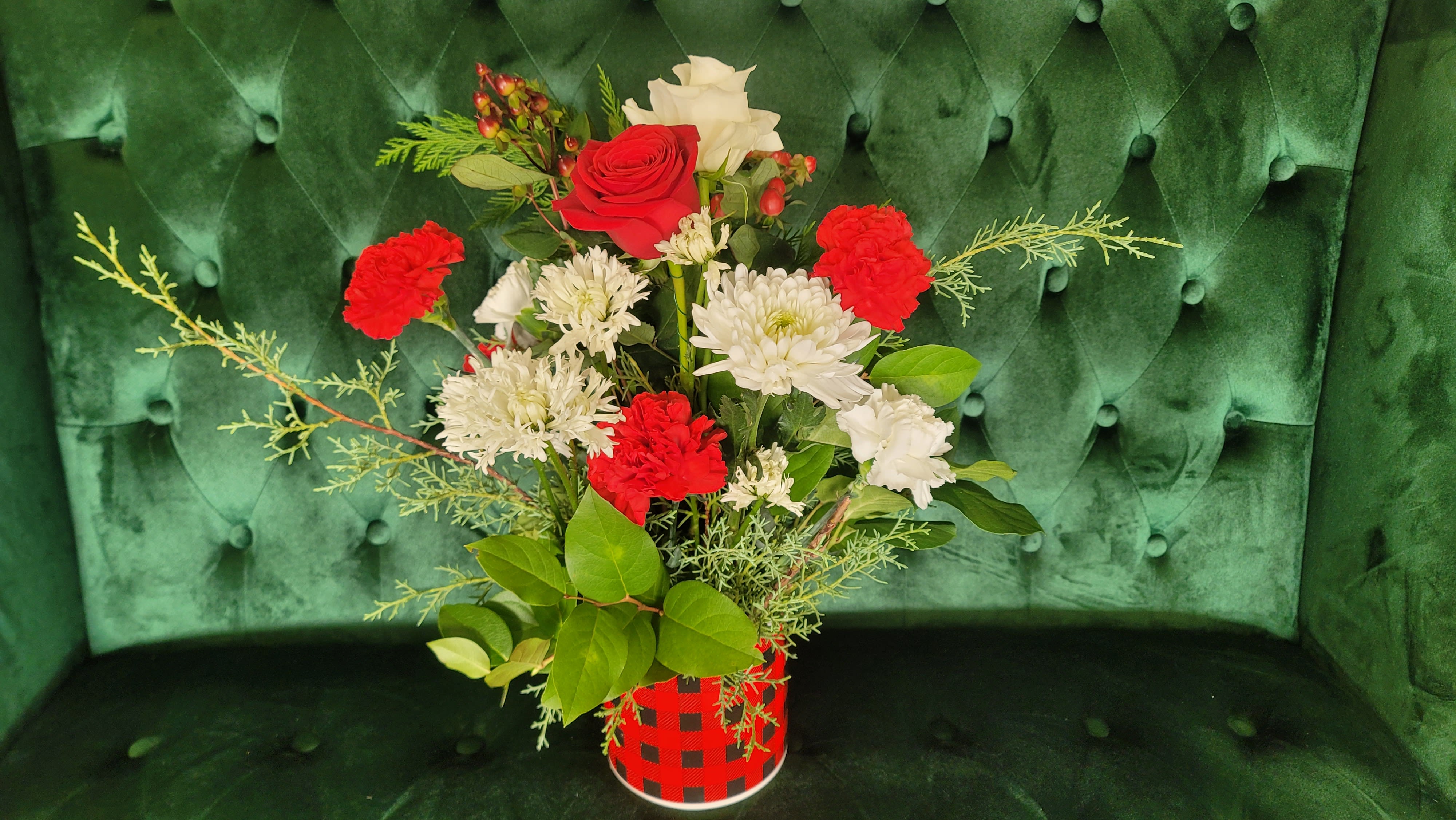 Classy Christmas  - a mixture of berries, red and white roses, red and white carnations , white poms and holiday greens in a holiday checkered vase.