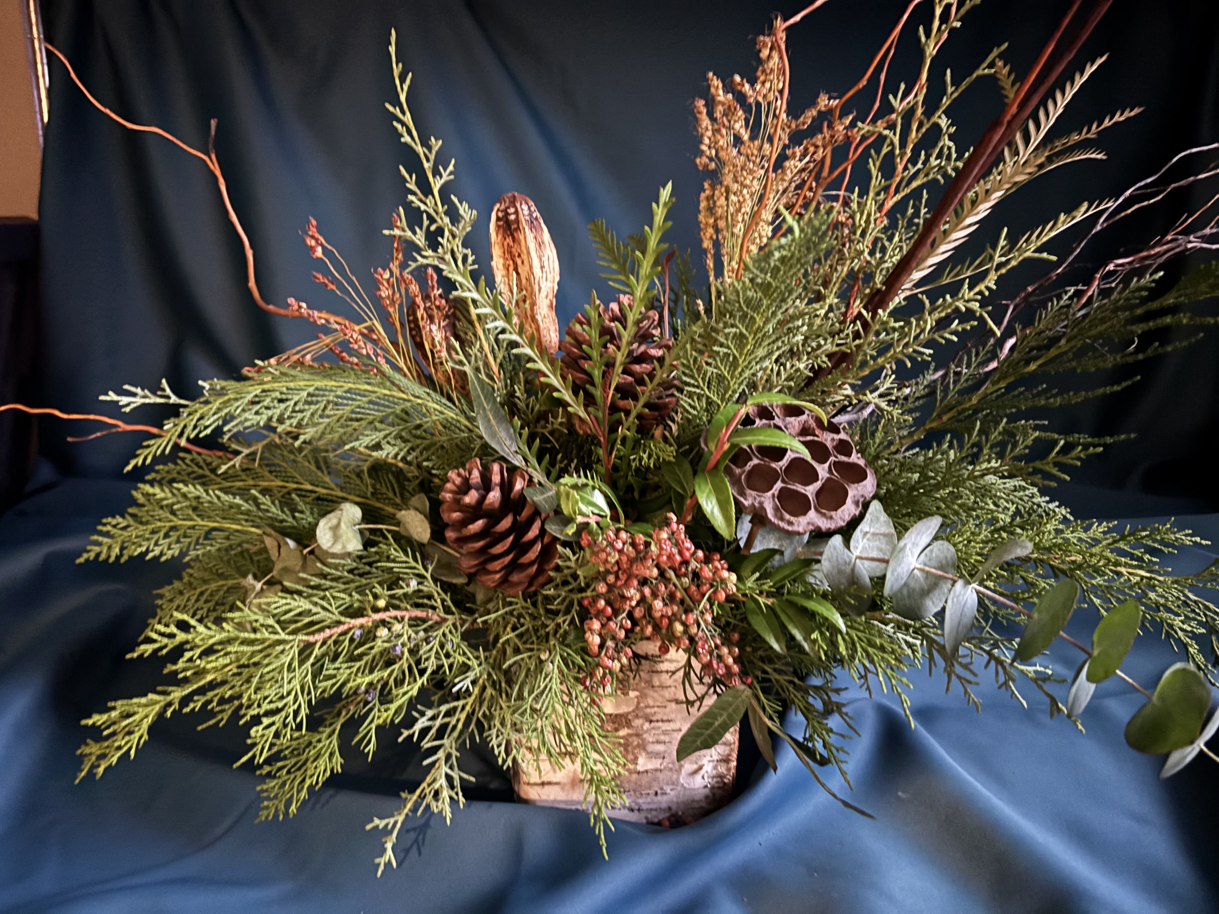 Designer’s Choice, ENCHANTING EVERGREENS - Indulge in an elegant arrangement of Christmas greens merged with holiday magic, suitable for decorating or gifting.  To add an extra layer of sophistication, blooms can be added for an additional charge.  Delivery and in-store pickup options are available. Photo shown reflects a $75 value.