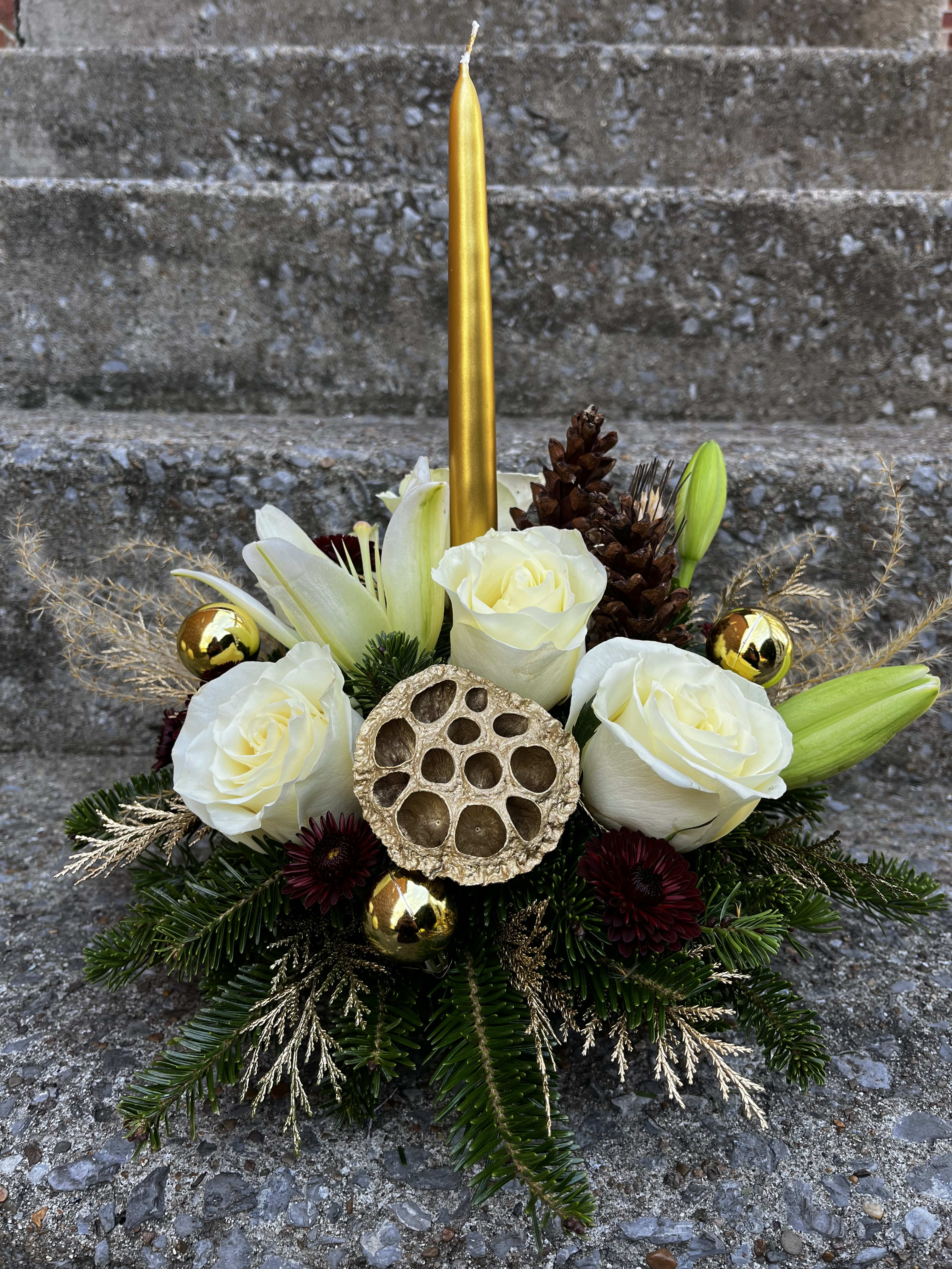 Golden Centerpiece  - This centerpiece has roses, lilies, mums, pinecones, golden colored Christmas greens, Christmas greens, a pod, Christmas ornaments, and a golden candle.