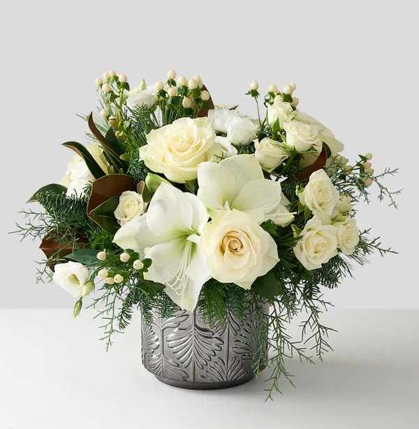 Amaryllis Glow  - Amaryllis Glow is an elegant White Amaryllis and Rose Holiday Centerpiece with Magnolia Leaves. It perfectly captures the serene beauty of a snowy, festive season. Dimensions: 12''H x 12''W 