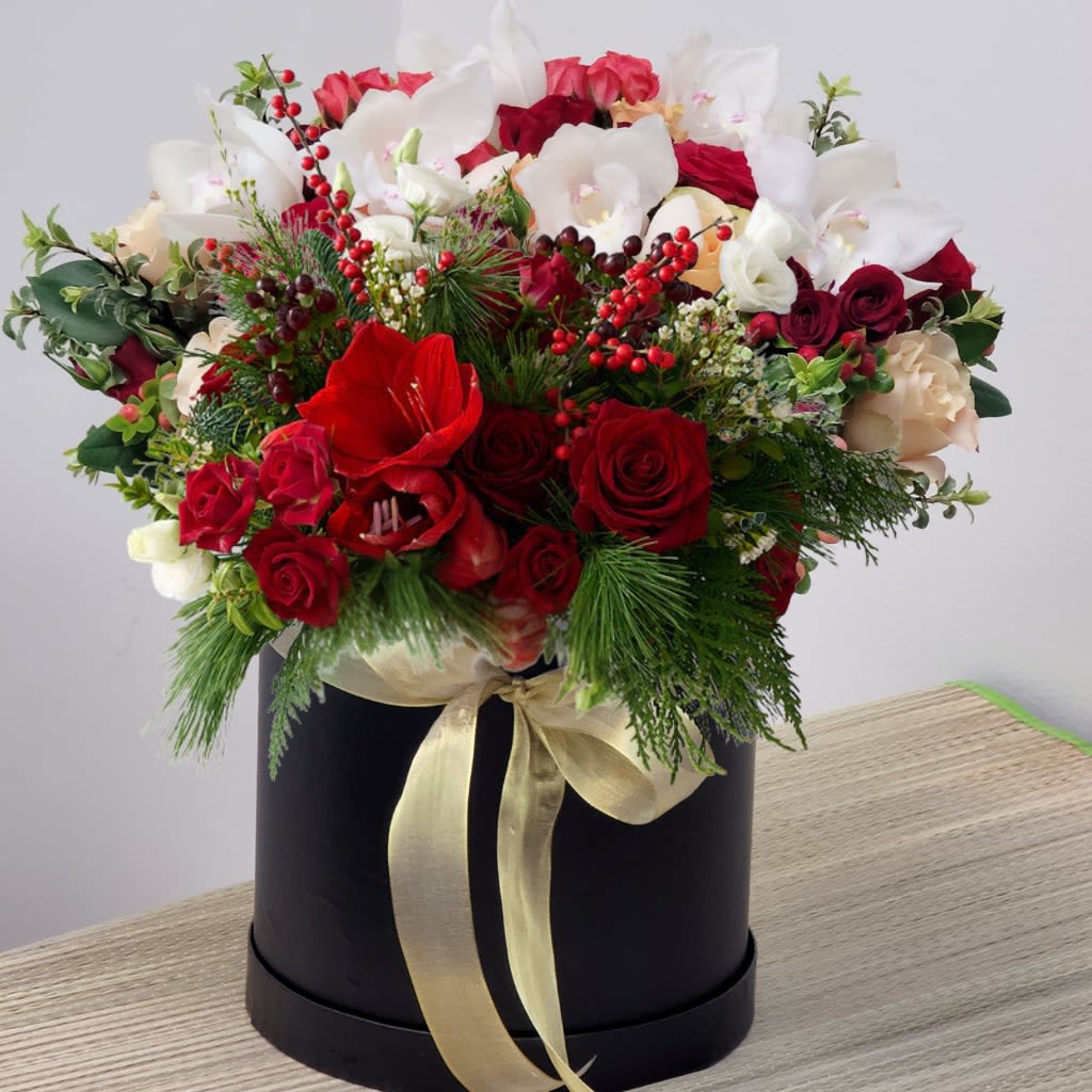 Amaryllis Giftbox Flowers - The Amarily is an exquisite celebration of seasonal elegance and timeless beauty. Featuring vibrant red roses, striking red amaryllis, and rich red berries, this luxurious arrangement is perfectly accented with lush winter greens. Carefully curated to create a medium-sized display, the Amarily embodies sophistication and warmth, making it an unforgettable gift or centerpiece to brighten any space during the holiday season.
