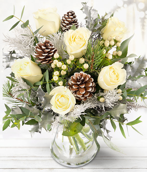 Frosted White Roses Bouquet - A festive bouquet featuring snowy white roses and frosted pine cones, arranged between an array of fragrant seasonal foliage