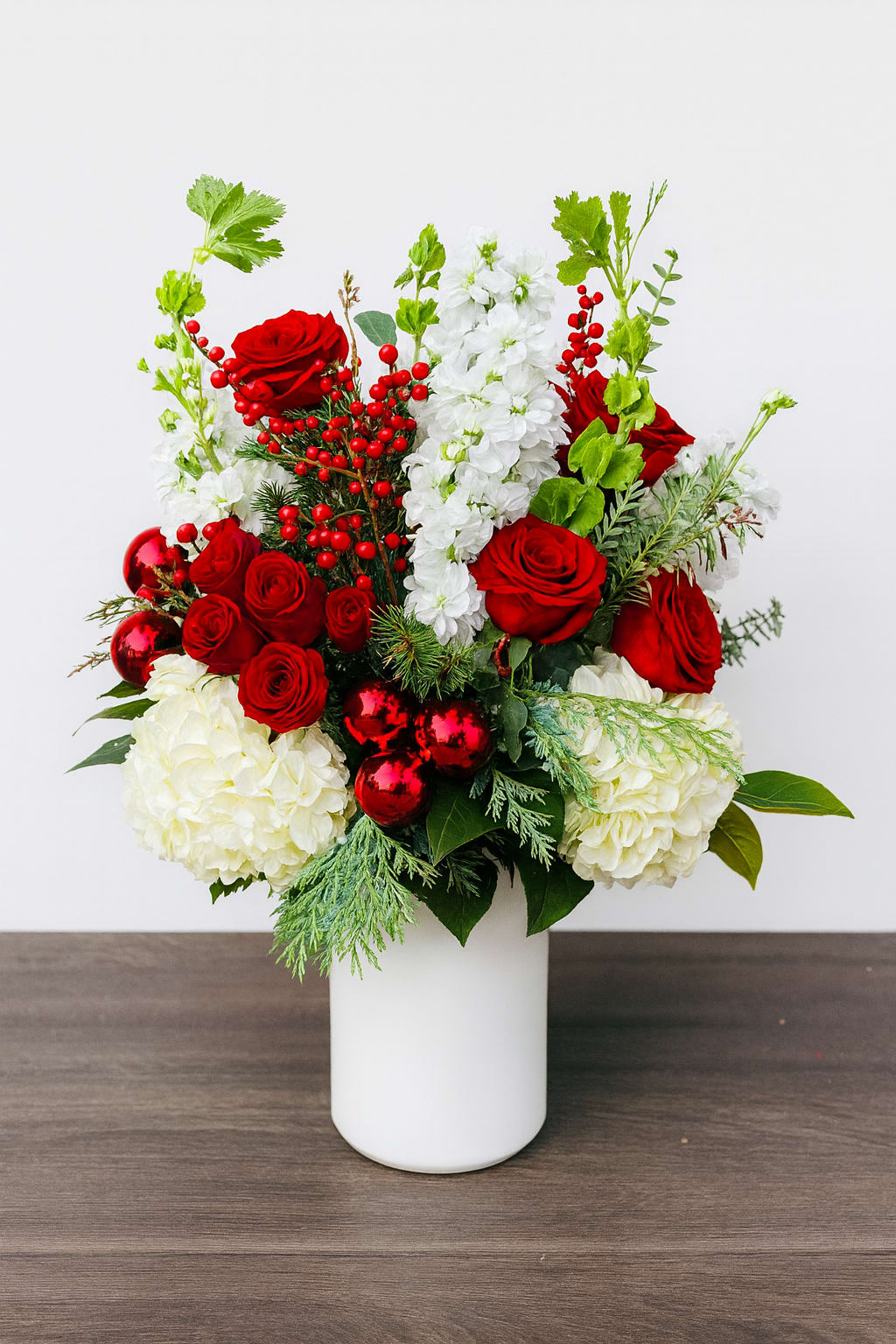 Holly Jolly - Bring festive cheer to any space with Holly Jolly, a bright and elegant holiday arrangement designed to delight. Featuring vibrant red roses, fresh seasonal greens, and soft white hydrangeas. Perfect for gifting, decorating the home, or adding a touch of holiday luxury to any celebration.  Handcrafted with premium blooms at Polk Street Florist and available for same-day delivery in San Francisco.