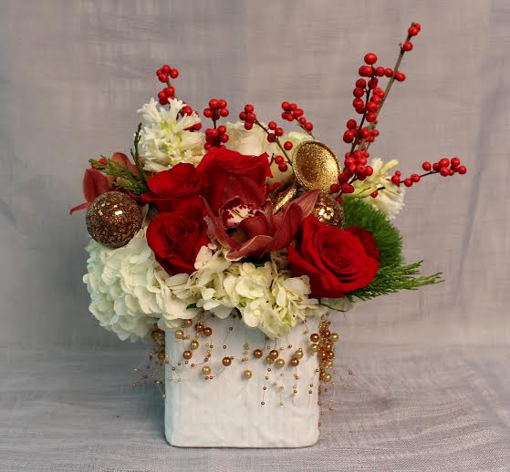 Red Berry Christmas Arrangement - This lovely Christmas arrangement features white hydrangea, red roses, ilex berries, cymbidium orchids, and holiday accents.